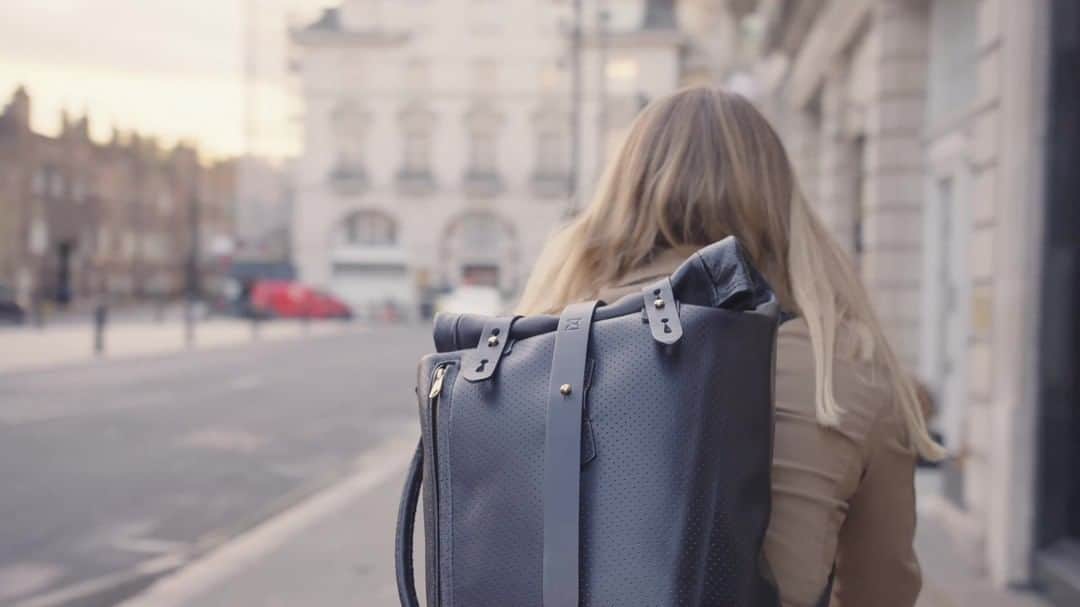 ジョンチャップマンのインスタグラム：「A cycling backpack that looks as good on the road as it does in the boardroom - what could be better?  In daylight our roll-top backpack with briefcase handle is the apogee of smart black leather discretion, ideal for the boardroom. And yet, at night, it will reflect car headlights revealing you and your brilliance for buying it!  What’s behind this solution? High quality perforated pinhole leather, behind which is a highly reflective material which shines through the pin holes when you need it to.  Chapman's timeless craft and design skills alongside capacious roll-top styling and reflective safety feature means that all you need to do is remember to remove your cycle clips and you are (as they say) 'ready to shine'!  Chapman bags - Handmade in Carlisle since 1984.   #ChapmanMade #Chapman #bags #leather #cycling #innovation」