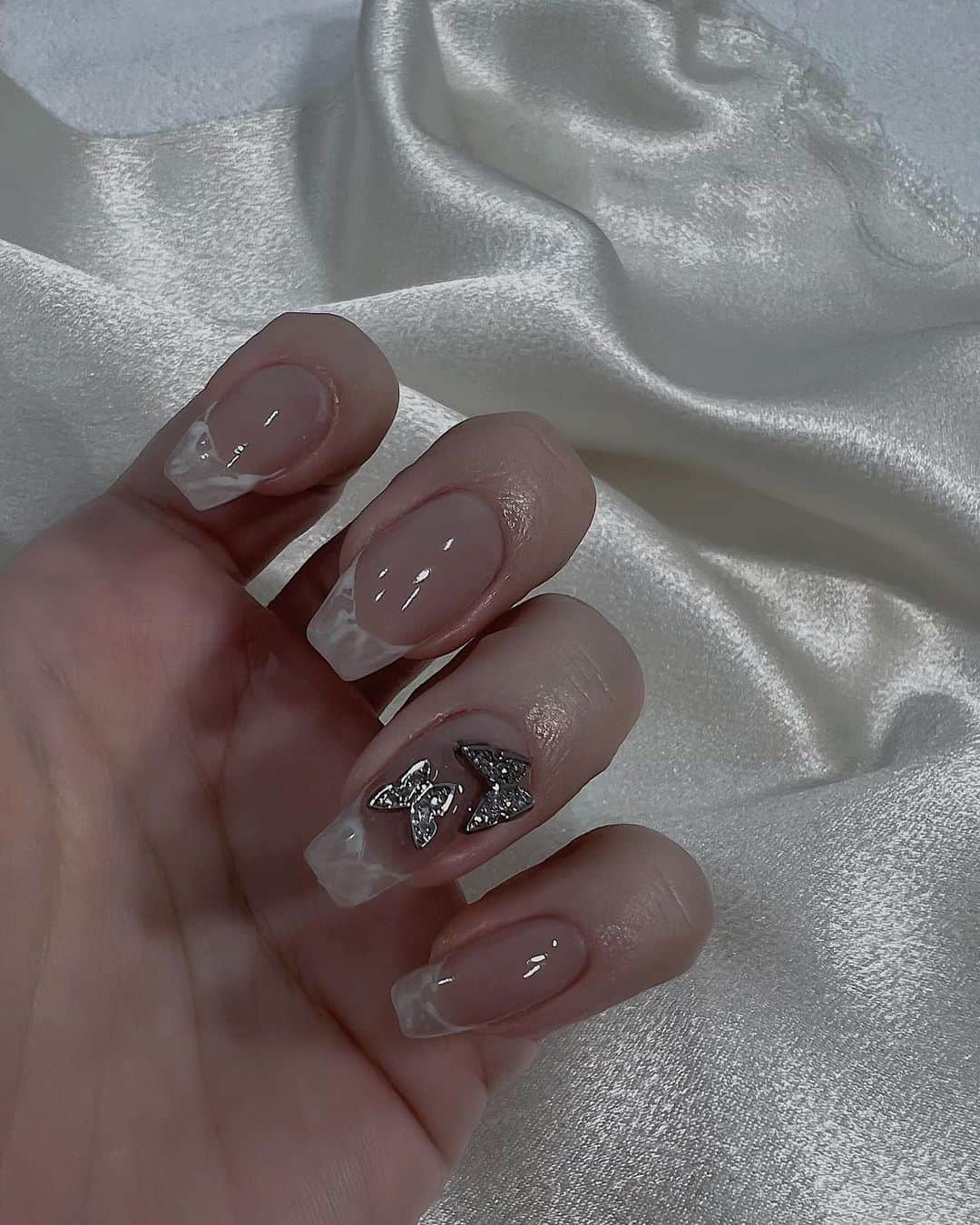 のインスタグラム：「Nail♡ @ellenail_shibuya   ヌーディーなピンクに、白マーブルのフレンチ🤍🤍 ミニ蝶々が可愛すぎて両手に飛ばしてもらいました🦋🥹  フットもピンクベージュ系で、輝きが綺麗なマグネットに、アクセントで先端に細くシルバーのライン🥰  サンダルの時期にマグネットネイル本当かわいい！🥲💓  elle nail渋谷店さん、ありがとうございました💅♡  ご予約はホットペッパーbeautyからがお得です🥳💖  #nail #フレンチネイル #ネイルデザイン #フットネイル #マグネットネイル #ellenail」