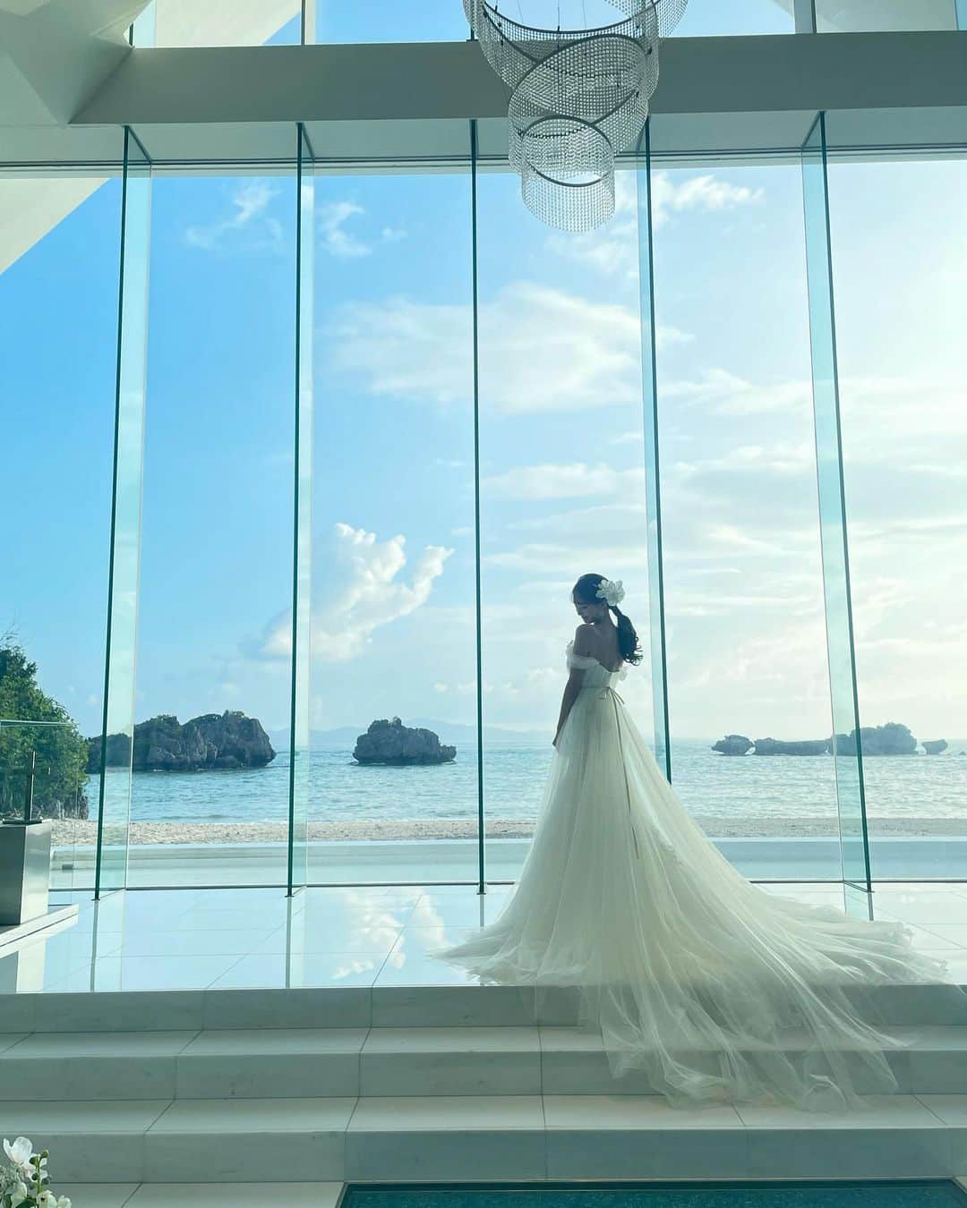 宮内理沙のインスタグラム：「オフショットラスト📸🌺 沢山載せてしまいましたがお付き合いいただきありがとうございました🙇‍♀️🤍  起きた時は雨が降っていたので撮影の時大丈夫かなと心配していたのですが本番では綺麗に晴れてくれて良かった😙☀️ 素敵な場所で天気にも恵まれて幸せでした☺️  そしてでこっぱちなのが昔からコンプレックスのうちの１つでお仕事でもプライベートでも恐らく全部出すことはなかったのだけれどこのヘアにしていただいて克服したかもしれない、、！改めてヘアメイクさんって凄い🧐✨✨  お仕事で色々なウェディングドレスやウェディングヘアを見させていただいているのでいつかの自分の結婚式の参考にしたいなと思っているのですがどれも良過ぎて全く絞れていないので早く絞らないとな〜と思ったり、 国内外の式場コーディネートやムービーや招待状の構図とかを時々見ては保存しているけどそういえばまだ結婚する予定ないんだよね😂💡  #色々先走っては目覚めています　 #自称晴れ女 #そろそろ自称なくしても良いかな? #ウェディングフォト  #リゾート婚」