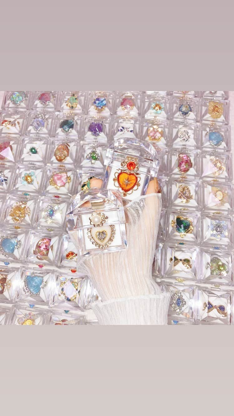 Sakikoのインスタグラム：「クリアケースに入ったマルベリコの指輪🏵💍  ずらっと並んでいるのは、秋コレクションを含めた発送待ちのリングたちです🎁 指輪のカラーに合わせたガラスビジューを、クリアケースに貼り付けて、専用のボックスにお入れし発送いたします。 無事に届きますように💫  #ハンドメイド #ハンドメイドアクセサリー #指輪 #リング　#発送準備 #梱包作業 #リングケース #フリーサイズリング #ハートリング #押し花アクセサリー #かわいいアクセサリー #kawaii #cute #kirakira #handmade #handmadejewelry」