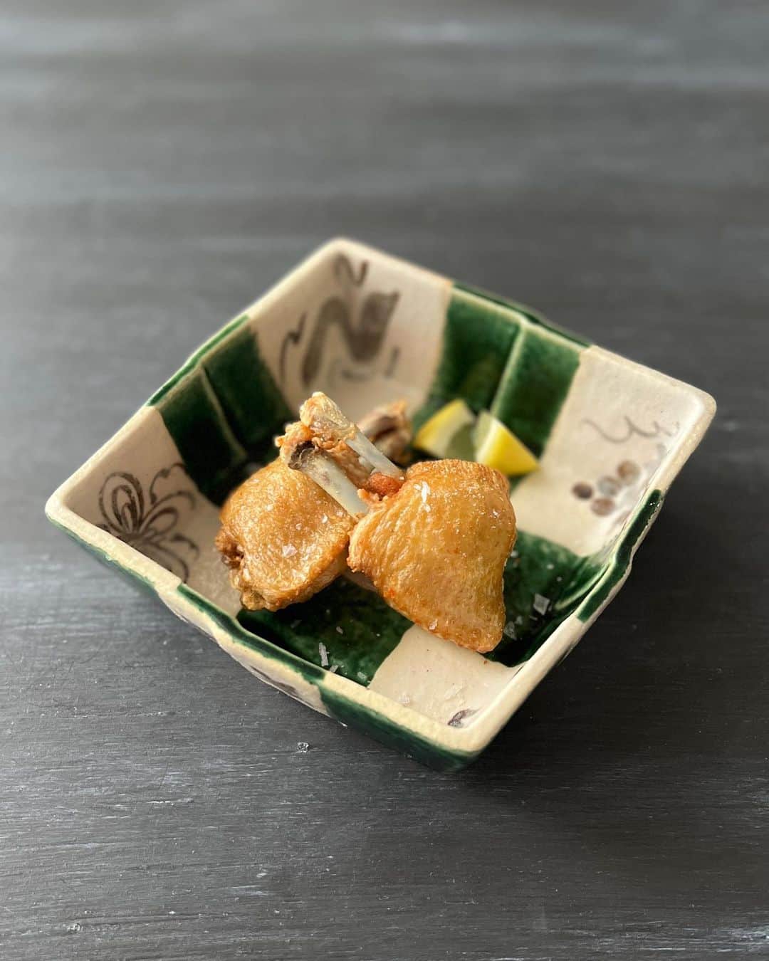 三島葉子のインスタグラム：「【おいしいひと皿】これは！と思われた方は京都を良く知る人かも知れません。 予約の取れない食堂の有名な一品のオマージュ。 手羽先をただ揚げているだけではなく、仕事がちゃんとしてあります👏 敬愛する料理家 田岡先生に教えてもらった隠し味もプラスして！ シンプルなお料理にはこちらの織部のうつわが映えるような気がして合わせてみましました✨  ①手羽先は関節より先をカットし、関節に付いた筋を筋切りし、身を手羽元の方向にギャザーを寄せるようにしごく。←コレするとすご〜く食べやすくなります！ 身を元に戻して軽く塩をし、ラップをしないで冷蔵庫で1日乾燥させる。  ②170℃の油でまわりがカリッとなるまで揚げる。2度揚げしても良い。  ③胡麻油で香りをつけ、塩を振る。←田岡先生仕込み！  ④柚子胡椒をそえる（切らしていたのでスタンダードにレモンを添えました）  作るのには時間が掛かるけど食べるのは一瞬です。みんな手羽先、好きですよね😉  ＃京都 ＃和食 ＃和食器 ＃手羽先  ＃予約の取れない食堂 ＃たち吉 ＃料理王国 ＃料理王国アカデミー ＃三島葉子」