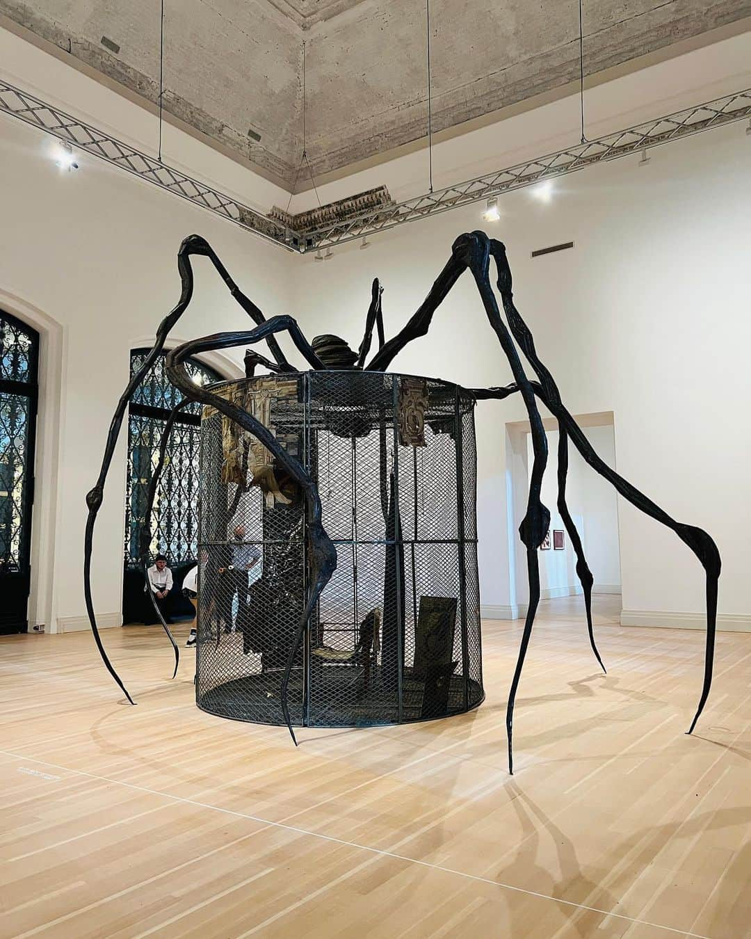 小柴綾香のインスタグラム：「📸2022.08.06  Louise Bourgeogs: The Woven Child  この夏ヨーロッパで観た展示で最も印象に残った、Gropius bauでのルイーズ・ブルジョワの展覧会。  1911年にパリに生まれ、数学や哲学を学んだというブルジョワは、その後結婚を機にNYに移住し、美術活動を始めた遅咲きの作家である。この展覧会では、彼女が2010年に亡くなるまでのキャリアの最後の20年間に焦点を当て、彫刻やインスタレーション、ドローイング、コラージュ、本、版画などベルリンでは初公開のものも含めた約９０点の作品を展示している。  終始作品を通して感じたのは、彼女の人生のあらゆる段階での記憶が物語的に共有されているという事。  中でも「セル」と呼ばれる空間インスタレーションは、金網の中に仕舞いこまれた彼女のトラウマ的な記憶の断片を覗き見ているよう。幼少期に過ごした自宅の模型や、お気に入りの身の回りの品や衣服から滲み出る、思い出や失われた時間が短編小説のように語りかけてくる。  また、六本木ヒルズ横の作品で誰もが見覚えがあるであろう蜘蛛の作品。「セル」をまたがっていて、どこかセルを守っているように見える。 そんな感覚と世間一般の蜘蛛が持たれているイメージが相反するような奇妙さを感じたが、のちにこの蜘蛛は母親を表していると知り、少し腑に落ちた。  加えてタイガーマスクのような顔の作品、ドローイングも本当に素晴らしかった...！まだまだ挙げるとキリがないので、それはまた後にアップしよう。  みなさんの今年最も印象に残った展示はなんですか？  #louisebourgeois #thewovenchild #gropiusbau #art #exhibition #berlin」