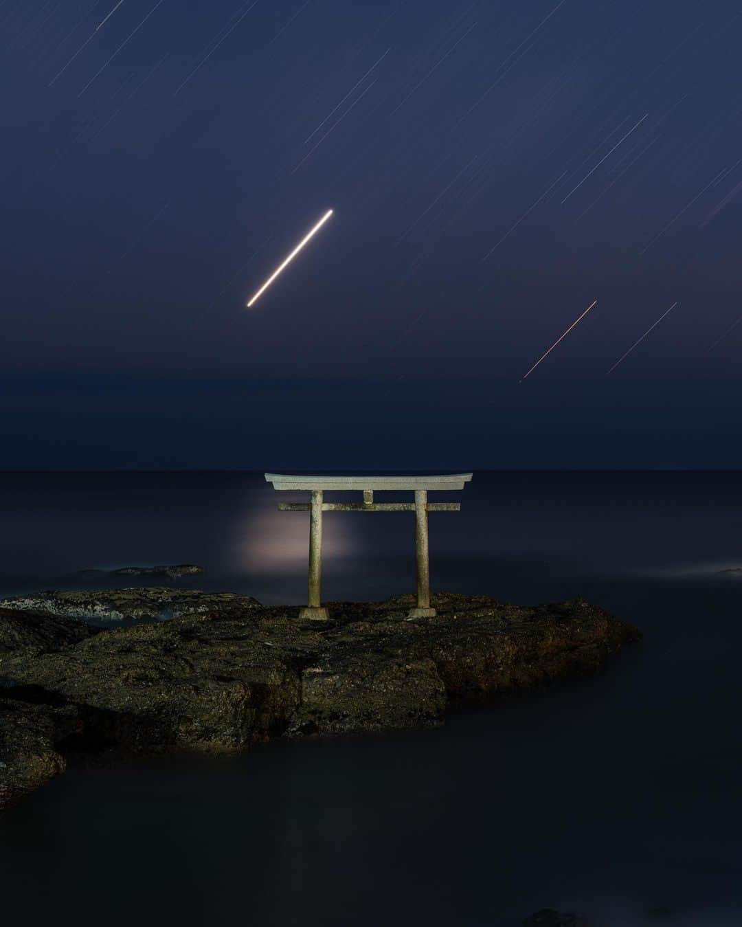 のインスタグラム：「夜明け前の神磯の鳥居⛩  神様が降臨したとされる大洗磯前神社前の海岸に建てられた鳥居。  ここに来ると、 太古の人が太陽や月、星、海に感謝し、畏れ、敬っていたことが体感できる。  波の音に耳を傾けながら、鳥居を眺める。  静かな時間、、 この印が僕らに大事なことを気づかせてくれる。  思えばさ、 自分らが目にする海や山、見慣れた景色も、鳥居は立ってないけれど、しめ縄はないけれど、そんな印はないけれど、きっとこの場所と一緒なのかもな、と思う。  公園に立つ巨木だって、名もない御神木なのかもしれない。 たまたま腰掛けた岩は、磐座なのかもしれない。  昔の人が感じれていた自然と共に生きる感覚、、 生かされているという感覚。  そんな想像力を持って、 日々生きていけるなら、 傲慢な気持ちなんかどこかへ消えて、謙虚で慎ましい自分を見つけることができると思う。  #神磯の鳥居 #大洗磯前神社 #神社 #感謝 #shrine #japantravel #japantrip #canon #canonR5 #beautifuldestinations #discoverjapan #discoverearth #voyaged #awesome_photographers #IamATraveler #wonderful_places #japanphoto #japanphotography #japan_of_insta #livingonearth #theglobewanderer」