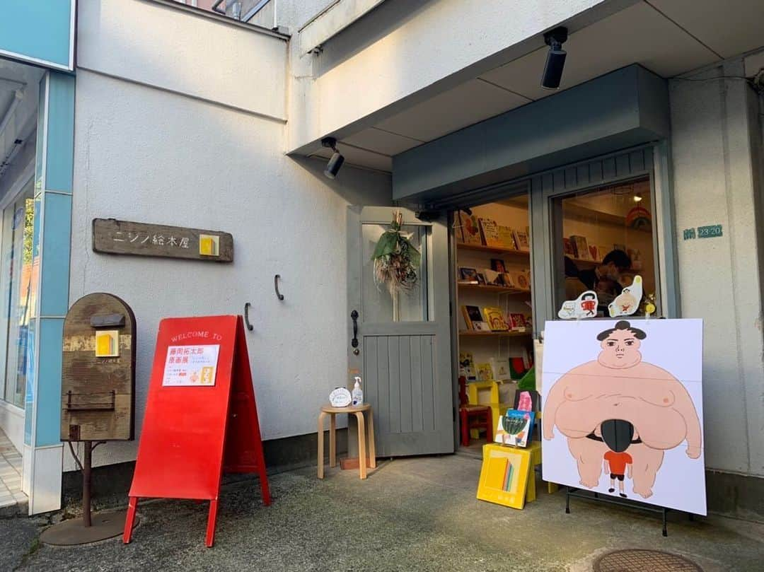 藤岡拓太郎のインスタグラム：「東京・都立大学駅近くの絵本専門店「ニジノ絵本屋」さんにて原画展が始まりました！  サイン本、たぷトート、マメパオ缶バッジ販売、特製フリーペーパー配布に加え、たぷの里制作ノートや顔はめパネルもお楽しみ頂けます。  『たぷの里』と『ぞうのマメパオ』原画展 1/7-1/30（定休日：火・水） 12:00〜18:00  #ニジノ絵本屋 #目黒区 #都立大学駅 #たぷの里 #ぞうのマメパオ #藤岡拓太郎  #ナナロク社」