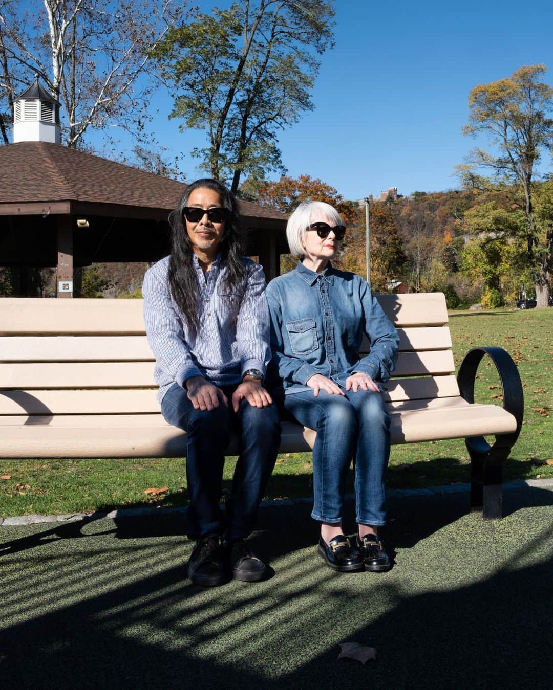 のインスタグラム：「Vintage Hipster Couple on Bench, Peekskill, NY.  circa 2022.   Calvin and I were a little ahead of the hipsters who migrated to Williamsburg, Brooklyn during the late 1990’s. We rented a loft in a former burlap bag factory on the South side. We were on the first floor and our loft was two levels as it contained what was formerly the loading dock. We saw the river and the Williamsburg Bridge from our huge window near the kitchen. We smelt the sweet boiling sugar from the Domino Sugar Factory. In our 40’s It felt like a place that was becoming, so were we.  My daughter left for college and we had room in our lives to fill. At around the same time I started a Ph.D program and Calvin began an MFA in Creative Writing. My home away from home was the bookstore Spoonbill and Sugartown where I could read about art and whatever postmodern philosopher was captivating me at the moment. Calvin hung out at Main Drag Music with other guitar heads. There were only a few places to eat. Mostly near the Bedford L subway station. There was a performance space called Galapogos, a former mayonnaise factory with a reflecting pool that was our cultural hub.  Calvin built a workspace the length of the sunken section of the loft where we worked side by side; alone but together. Bookshelves above went all the way to the 14 foot ceilings. While living there, Calvin named us the vintage hipsters.   While we were part of the first wave of gentrifiers, the second overwhelming tide found our small loft building surrounded by much taller ones blocking our view. Mice from all the construction scampered across the wide, pine floor boards at random times of night and day. We sadly left our beloved loft and headed to another site of becoming: Long Island City.  Eventually we landed in Manhattan.  So here we sit in Peekskill, now in our 60’s and in another place that’s becoming. It will be exciting to see what will become of us here. Because we are a couple that’s always becoming. Who will you become?  #vintagehipsters #becoming #evolving #reinventing #thecouplealwaysbecoming #williamsburg」