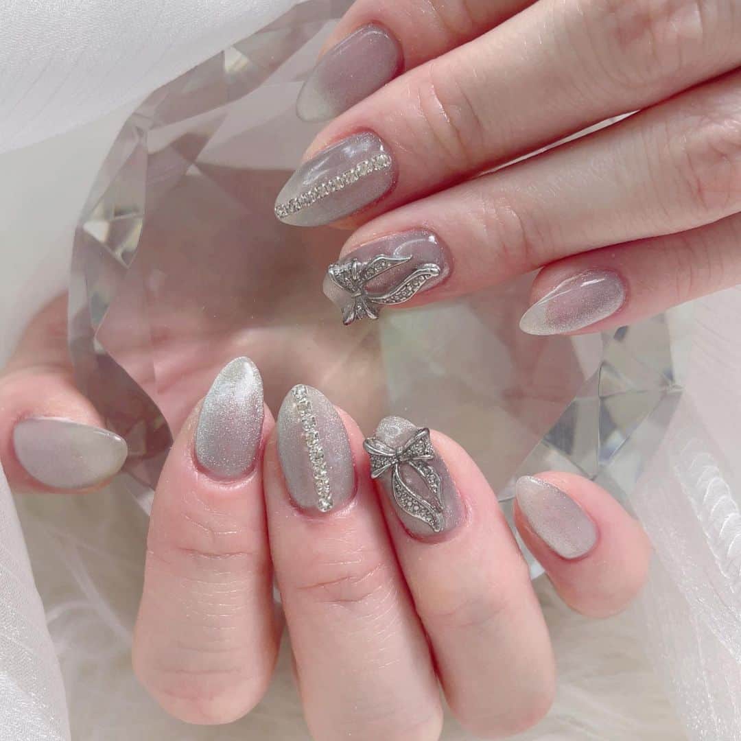 のインスタグラム：「雪の中行ってきた🥹❄  ホワイトシルバーのマグネットにリボンとビジューライン🎀  . .  . #冬ネイル #冬ネイルデザイン  #パラジェル #ワンホンネイル  #ジェルネイル #ジェルネイルデザイン  #パーツ #パーツネイル #ビジュー #ビジューネイル #マグネットネイル #マグネットネイルデザイン #シルバーネイル」