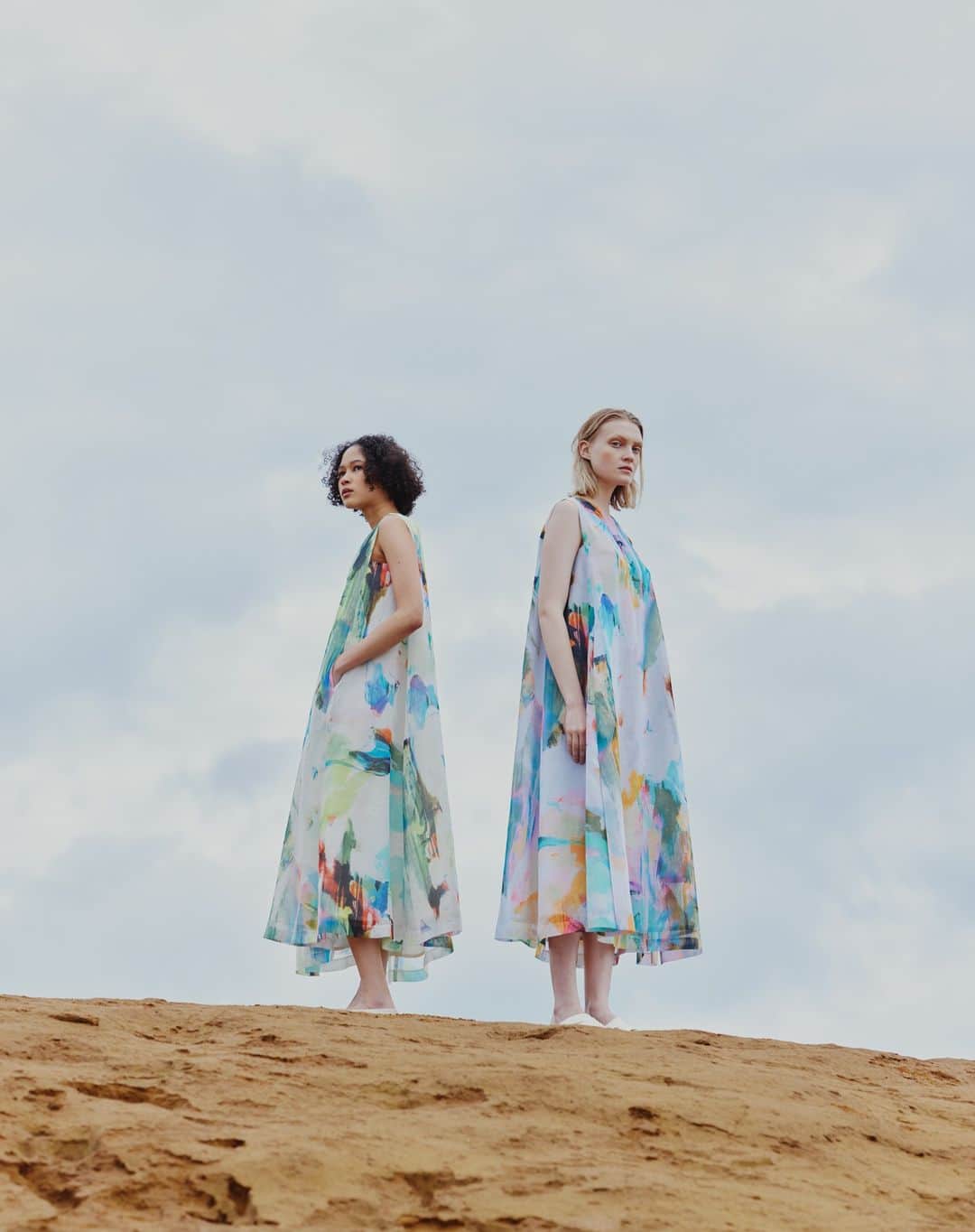 H/standard（アッシュ・スタンダード）のインスタグラム：「Printed Sleeveless Maxi Dress シーズンテーマの”Every cloud has a silver lining.”に合わせて雲の裏側がシルバーに輝くイメージのライニングや雲の隙間から差し込む光を@kanakosasaki_elhd が再解釈し、表現したアートプリントをシアオーガンジー素材に乗せたクリーンなマキシドレス。  #stumbly #スタンブリー #newstandard #artprint #paintart #newheritage」