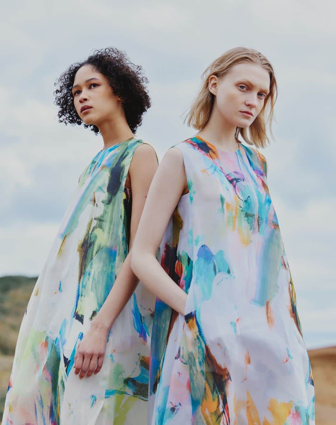 H/standard（アッシュ・スタンダード）のインスタグラム：「Printed Sleeveless Maxi Dress シーズンテーマの”Every cloud has a silver lining.”に合わせて雲の裏側がシルバーに輝くイメージのライニングや雲の隙間から差し込む光を@kanakosasaki_elhd が再解釈し、表現したアートプリントをシアオーガンジー素材に乗せたクリーンなマキシドレス。  #stumbly #スタンブリー #newstandard #artprint #paintart #newheritage」