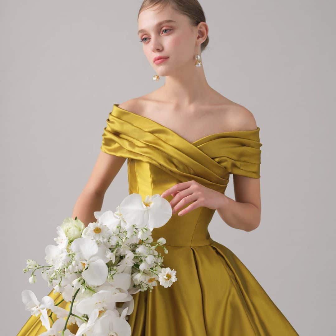 TAKAMI BRIDALさんのインスタグラム写真 - (TAKAMI BRIDALInstagram)「Yellow Claret / イエロー・クラレット  鮮やかなイエローの色合いと光沢感が、リュクスな雰囲気を叶える一着。 デコルテラインを美しく見せてくれるオフショルダーは、花嫁様をより可憐な印象に。 どの角度からも美しいフォルムに見えるようスカートにはたっぷりのギャザーを施し、シンプルで洗練されたデザインでありながら優美さを感じさせる一着に仕上げました。  ※バックリボンは取り外し可能です。」3月19日 12時47分 - takamibridal_costume