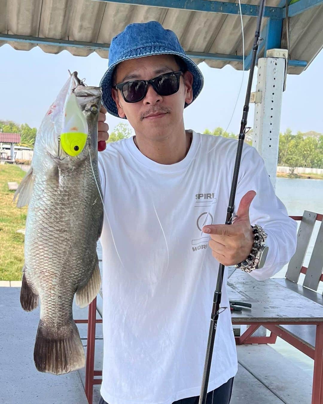 佐々木洋平のインスタグラム：「出張でタイに🇹🇭  今回はムエタイ界のスーパースター  吉成名高選手がラジャダムナンワールドシリーズことRWSに出場するので私もタイにきました。  25日の22時15分から試合開始です。  また明日ストーリーで告知しますので  みなさま応援よろしくお願い致します🤲  そんな私は今回もバラマンディをしばきに行ってきました🐟  あー難しいw  タイいろんなところみれてめちゃ楽しんでる　  #タイ  #タイバンコク  #バラマンディ  #釣り  #fishing #fishinglife」