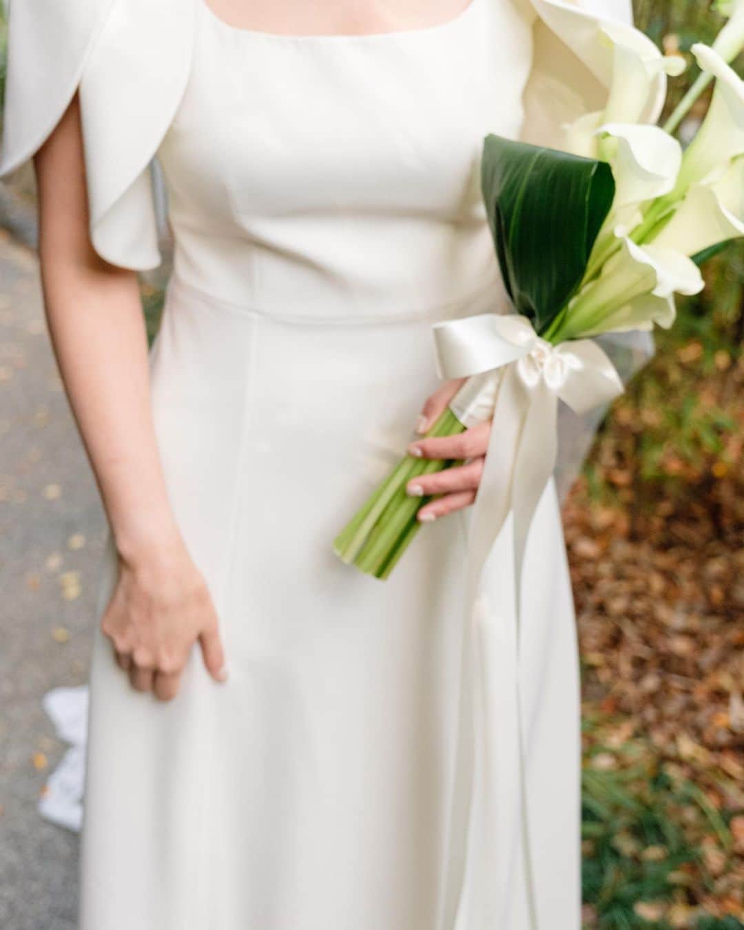 Shinjyu Lou Reid/リード真珠のインスタグラム：「Wedding moments I think about A LOT 🥰  1着目は、ロイヤルウェディングのテーマに沿ってシンプルに🕊 その分ヴェールはワンポイントのお花💐  極限までシンプルなシニョンスタイルと、バトントワリングしていた時の個人競技大会のために作ってもらったスワロフスキーのティアラ💎 挙式のピアスとネックレスはママの結婚祝いでもらったもので 披露宴入場はアメリカのおばあちゃんの形見のイヤリング👵  真珠の名前はアメリカのひいおばあちゃん「パール」からもらった大事な名前だからパールアクセサリーはマストでした。 おばあちゃんからの形見をつけたのは、 ママがアメリカに行って結婚した時にすごく良くしてもらったらしい。私は会ったことないおばあちゃんだけども、ミドルネームの「ルー」はおばあちゃんからもらったお名前で宝物。  参列していない大切な家族のことを思えるように 身に纏うことができて嬉しかった😢  披露宴のドレスのリボンは 夫のジャケットに合うようにブラウンのリボンをユザワヤで買って、ピアスもインスタで見つけたもので🥰  ドイツ🇩🇪から帰国して参列した妹は 結婚式のテーマのクリスマスにそってグリーンのドレスを買って、ツリー🌲になろうとしたらしい。」