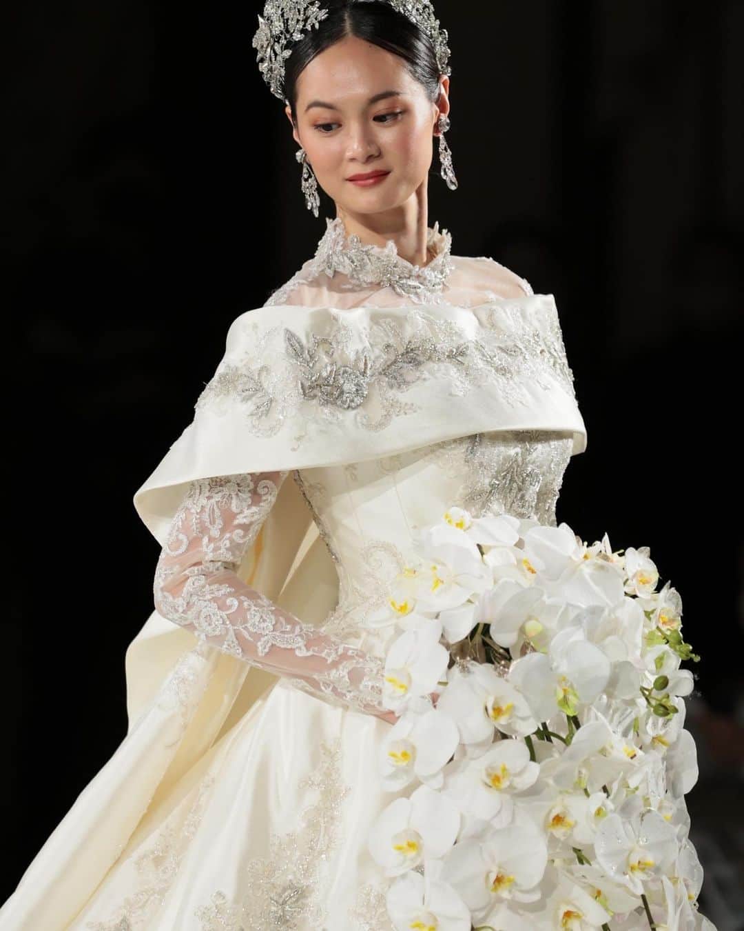 yumikatsuraさんのインスタグラム写真 - (yumikatsuraInstagram)「* 一際会場をわかせたのは、ロイヤルウエディングを彷彿とさせるようなシルバーのザリワーク刺繍とコードレースをふんだんに使用したこちらドレス♡ ⁡ 宮廷衣装のように高貴であり、主役としての花嫁様の存在感を圧倒的に印象付ける事でしょう✨ 素材、刺繍、縫製共に拘り抜いたオートクチュールブランドだけが製作可能なユミカツラならではの1着です💍 ⁡ ＊～＊～＊～＊～＊～＊～＊～＊～＊～＊～＊～＊～＊ ⁡ ショーの模様を特別公開中📸 https://www.yumikatsura.com/newjapanesewedding ⁡ . @yumikatsurajapan  @meiji_kinenkan_official  #ウエディングドレス #ウエディングドレス選び#結婚式ドレス #プレ花嫁𝟤𝟢𝟤3 #運命のドレス #桂由美 #桂由美ドレス #𝗒𝗎𝗆𝗂𝖻𝗋𝗂𝖽𝖾𝗌 #𝗒𝗎𝗆𝗂𝗄𝖺𝗍𝗌𝗎𝗋𝖺 #おしゃれ花嫁 #大人花嫁 #運命の一着 #ファッションショー #ロングトレーン #プリンセスドレス #ウエディングドレス試着」3月15日 17時44分 - yumikatsurajapan