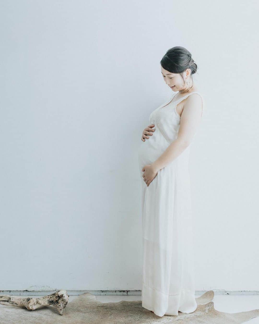 美甘子のインスタグラム：「妊娠期の記録⑤ 【マタニティフォト🤰2】 @holidaysphotoservice さんで撮影していただいたマタニティフォト2。ドレスワンピースがレンタルできるのですが、色んな色や素材のものの中から、この白い（アイボリーに近い）素敵なドレスワンピースにしました。 普段、二の腕が太いため…ノースリーブを着ることはないのですが、このドレスのデザインが綺麗だったので、思い切って二の腕出しをしました😂でもそれも思い出になるので良かったなと思います。 ご夫婦で営まれている素敵なスタジオで色んなパターンで撮影していただき、ありがたかったです☺️ #holidaysphotoservice  #マタニティフォト」