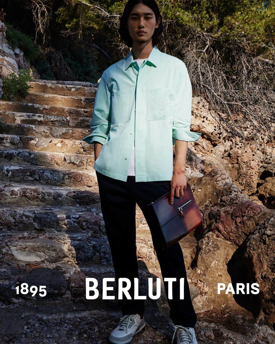 ベルルッティのインスタグラム：「- THE MOOD: SUMMER 2023 BY #BERLUTI -   Sunlight trickles through the trees, highlighting a shirt-jacket featuring workwear-nodding patch pockets with embroidered Scritto, worn over a T-shirt and trousers. Matched with a Venezia patchwork Nino clutch, it makes for an all-around day-to-night look.   Now available online and in-store.  Styling by @virginiebenarroch  Photography by @anthonyseklaoui   #BERLUTIDRIVE」
