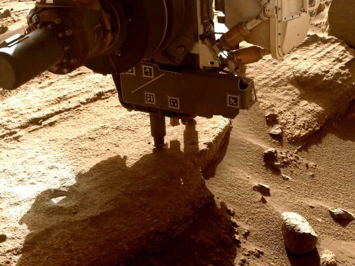 NASAのインスタグラム：「Back to the grind  Our Perseverance Mars rover collects a sample from an outcrop the science team calls “Berea” using a coring bit on the end of its robotic arm. These images were taken by one of the rover’s front hazard cameras.  A key objective for Perseverance’s mission on Mars is astrobiology – the search for signs life beyond Earth. The samples of Martian rock and dust that Perseverance takes are intended to be collected and returned by future missions in partnership with @EuropeanSpaceAgency for analysis on Earth.  Image descriptions: 1. A short video clip shows NASA’s Perseverance Mars rover collecting a sample from a rocky outcrop. Tailings pile up around the coring bit as it grinds into the rock.  2. A wider view of the rocky outcrop the Perseverance science team calls “Berea” after the NASA Mars rover extracted a rock core (right) and abraded a circular patch (left). Part of the rover's wheel can be seen in the lower left. Credit: NASA/JPL-Caltech  #NASA #NASAJPL #NASAPerseverance #Mars #Space #Planets #SolarSystem #Astrobiology」