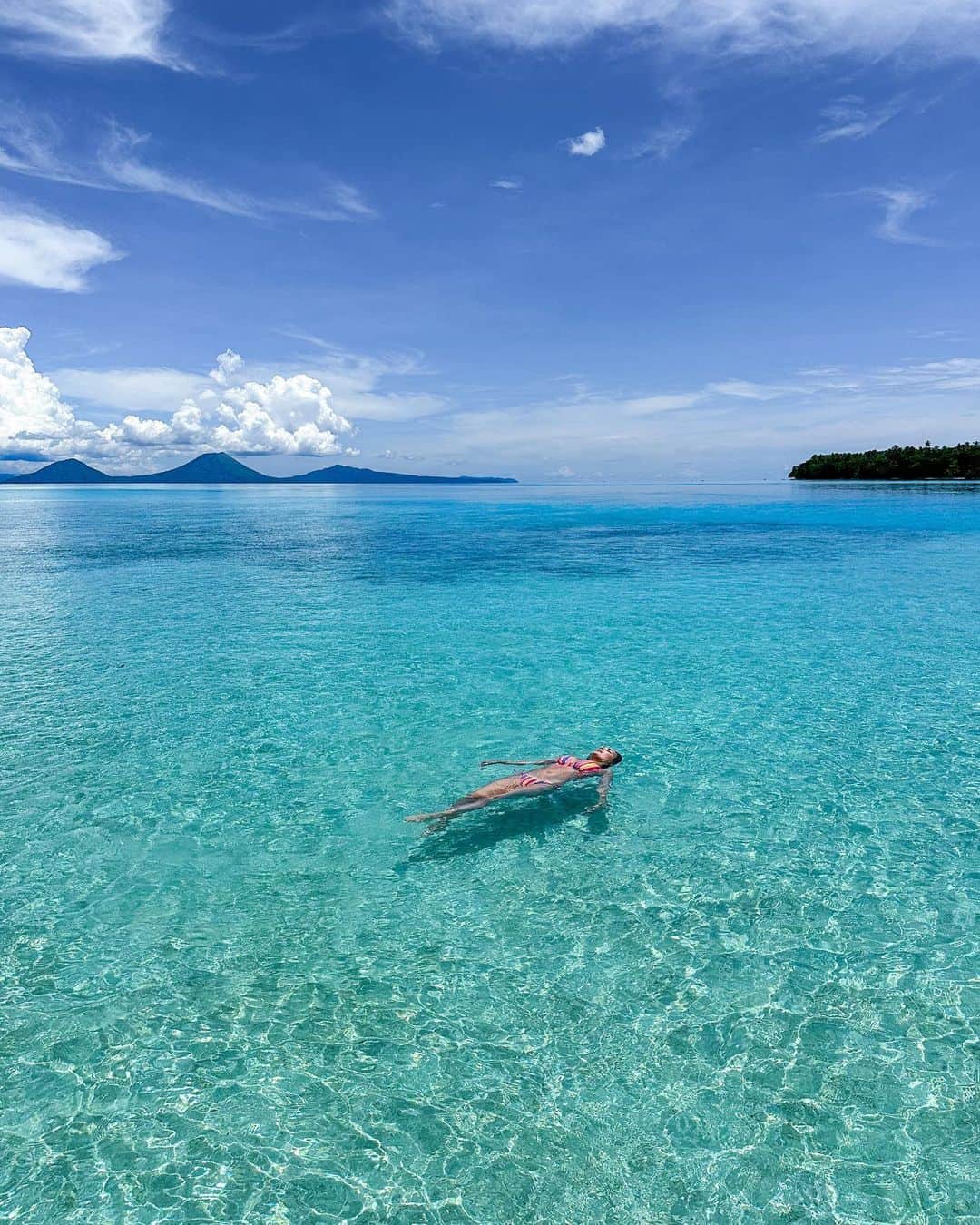 アリサ・ラモスのインスタグラム：「Just existing in Papua New Guinea is like living in a photo. And the only way to truly convey the beauty of what I saw, is through photos like these, because sometimes videos just don’t capture the art of nature and moments! Do you agree?  I had heard that it was beautiful there, and assumed as much given its location, but when I finally saw it in real life, it was completely unexpected. Surreal, raw, and just endless beauty.  The first thing I noticed was how crystal clear the water is, and the abundance of colorful sea life below that you can see even from the surface. (Those dots in the third pic are all starfish!)  Then it was the lush drops of jungle that dot the sea in the form of islands, with a never ending view of three volcanoes on the horizon.  It’s something really special to feel like you’re living in a piece of art! I hope more people will get this experience in PNG!   Reminder: I only recommend going to PNG with an established organization. We will have more info soon on that!  #pngpride #papuanewguinea #dukeofyorkislands #pngtribal #pngtribalfoundation #mylifesatravelmovie」