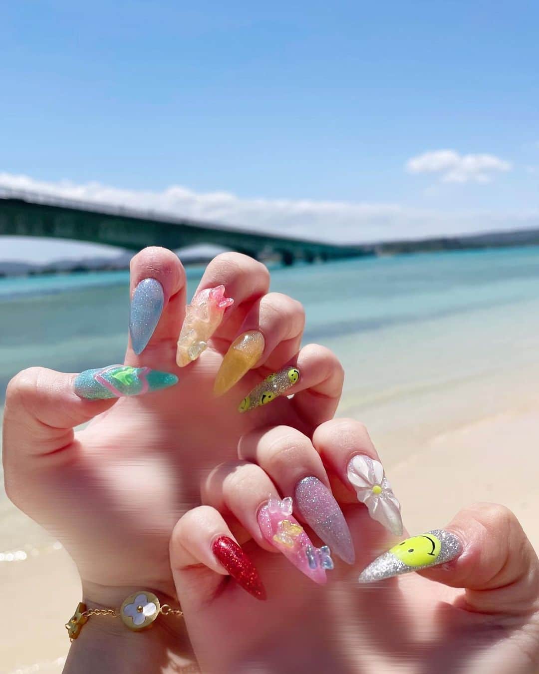 のインスタグラム：「🐚New Nail🫧‪  沖縄と髪色に合わせてカラフルにしちゃいました🌈 今回はニコちゃんと立体のお花と立体のハートと蝶々がいますεïз❤︎ パステルカラーだからほんと綺麗な海に合ってて映え映え✨️  @ribbon.nail_chihori さん今回もありがとうございます☺︎」