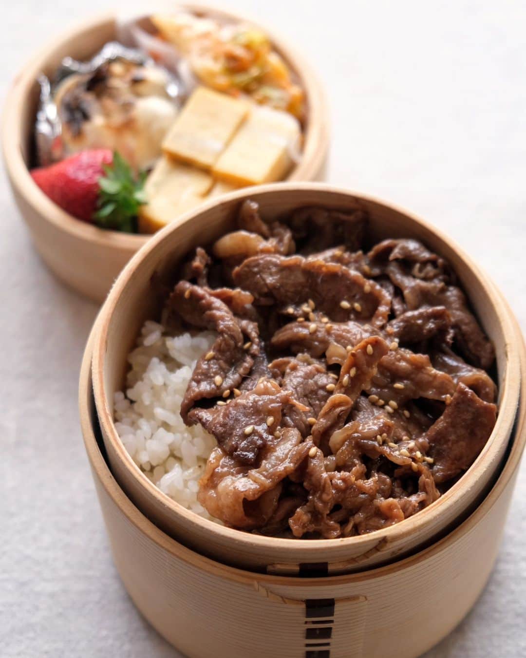 わたをのインスタグラム：「牛焼肉弁当  牛バラを焼肉のタレで焼いただけ弁当。焼きにんにく、わさびの卵焼きにキムチ。イチゴつき。３枚目に朝焼けを浴びる🍣  朝の散歩中、道端の草むらにペットフードを撒いてあるのを見つけたよ。しかも輪切りの赤唐辛子もたくさん混ざってて、おすしちゃんが口にしてたらと考えるとゾッとした。とりあえず土をかぶしておいたけど大丈夫かな🌶  #わた弁 #弁当 #お弁当 #焼肉 #yakiniku #bento #Yummy #delicious #Japan #Japanesefood #Japaneselunch #bentobox #lunchbox」