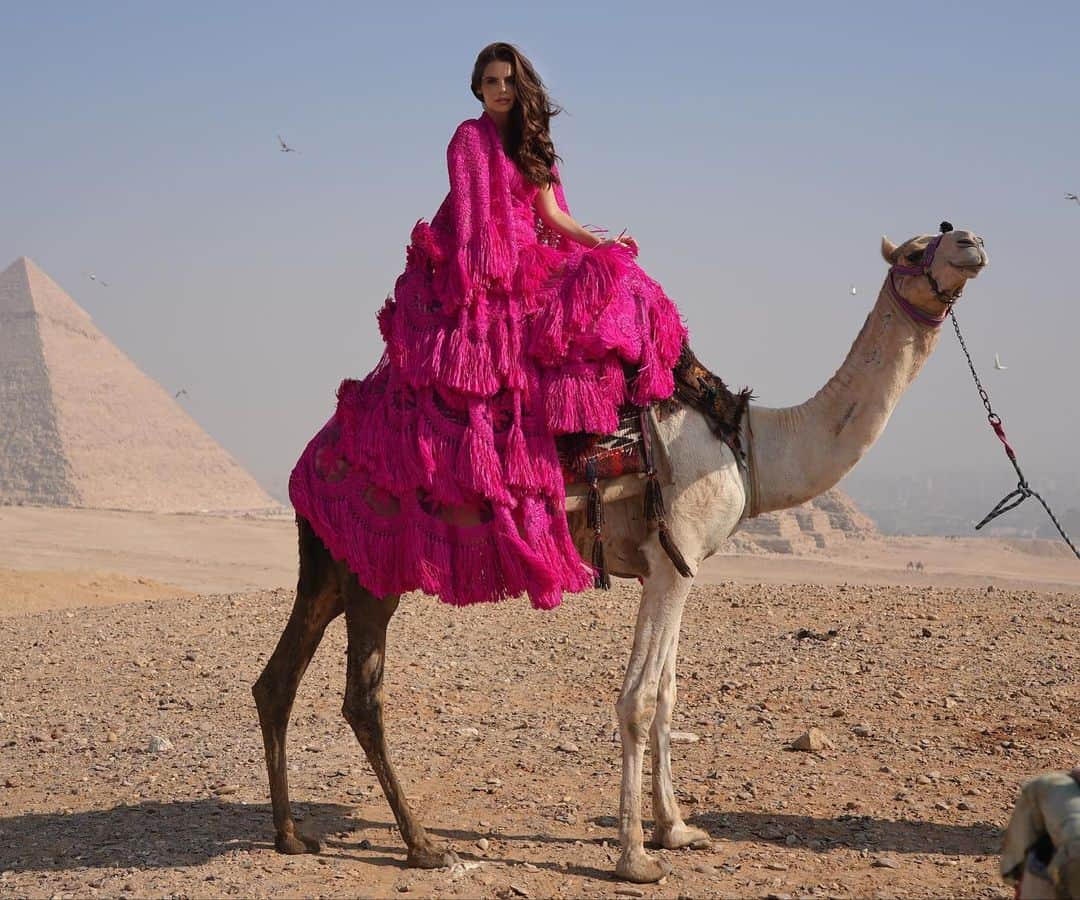 ナイーム カーンのインスタグラム：「Wanderlust. Naeem Khan in Cairo Egypt. Pre Fall 2023. Fuchsia raffia tiered long cape and gown. #NKPreFall2023」