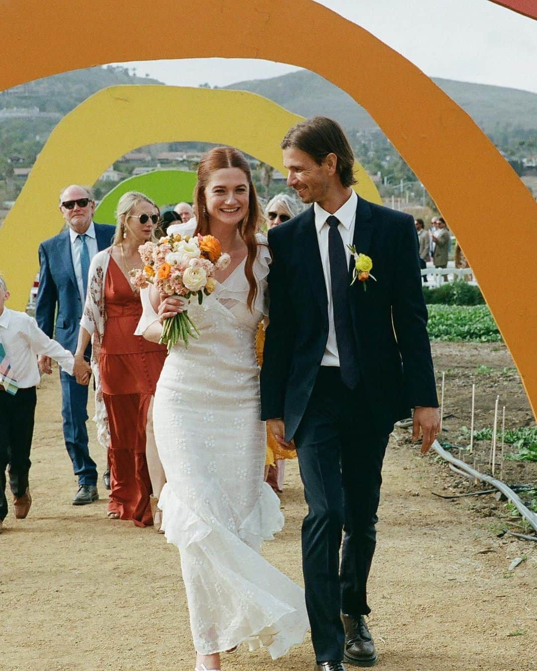 ボニー・ライトのインスタグラム：「Harry Potter actress Bonnie Wright's wedding was a celebration of love, community, and sustainability. 🌍💐  "It was important to reflect our love for the environment and use sustainable materials instead of any single-use packaging, lean into our creativity and make things ourselves, and source everything as locally and seasonally as possible," @thisisbwright shared with Brides.   See all the details from their magical wedding at a California farm at the link in bio.  📷: @st.chelle 📋: @__abbyandcaroline 💐: @pigsty 👗: @happyisles_salon 💍: @wrightandteague」