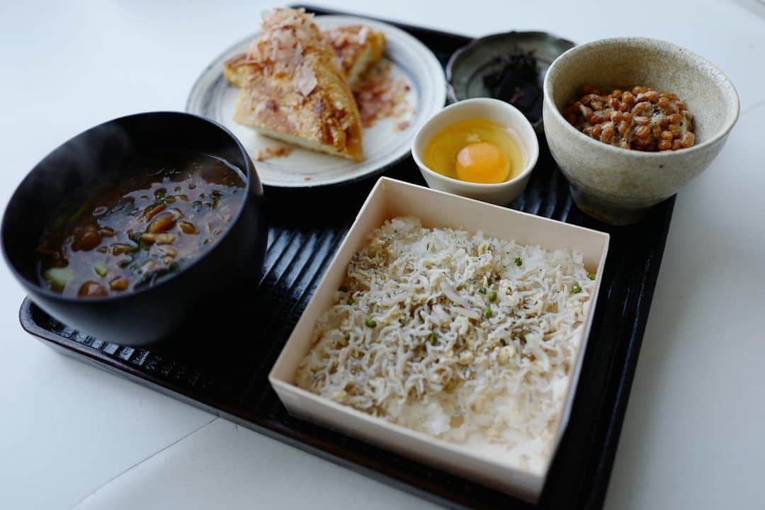 行方 久子 Hisako Namekataのインスタグラム：「#ひさこのおうちごはん 宮坂のお土産でいただいたじゃこ山椒乗せごはん&昆布をメインに とおの屋の納豆、どこかのいい卵、福井県谷口屋の大きな油揚げで朝ごはん。  お味噌汁はなめこと茗荷と小松菜🥬 （ごはんとお味噌汁の位置は間違えた🙄）  佃さん @tsudamoku のお盆でさらに贅沢感🖤  ごはんが欠けてるのは、我慢できなくて前の日の夜につまんだからw」