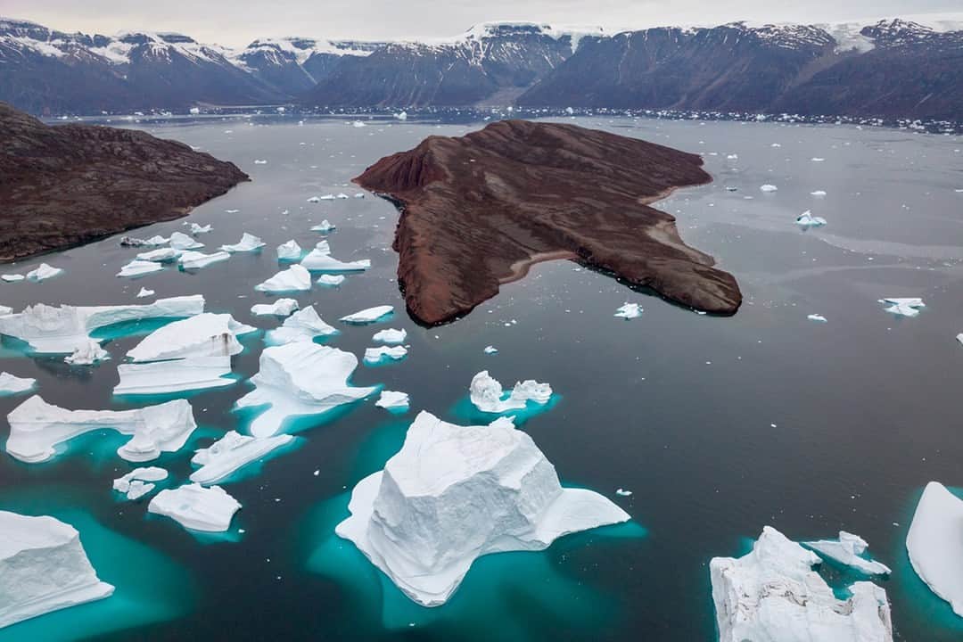 National Geographic Travelさんのインスタグラム写真 - (National Geographic TravelInstagram)「Photo by @mattborowick | Many of these icebergs are the size of small sports stadiums if you can believe it. They are stuck in place most likely touching the ground in this shallow water area between two land masses close to together. From our perspective the mass to the left is a mountain called Hermelintop and the island to the right is known as Red Island, named for its vibrant red sandstone. This part of the Scoresby Sund, in Eastern Greenland is unofficially called the “Traffic Jam” or “Iceberg Graveyard” as many icebergs get stuck in place when they drift into it. This image was created during a licensed drone flight and was taken in accordance with local regulations. Please follow for more pictures like these at @mattborowick #iceberg #greenland #nature #explore #adventure」4月2日 1時00分 - natgeotravel