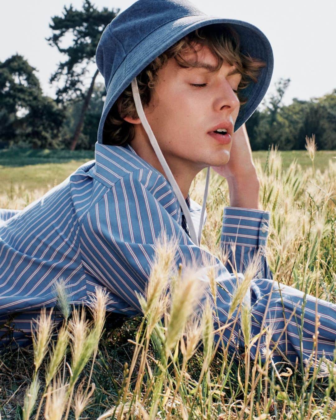 アーペーセーのインスタグラム：「A collection that reinterprets the distinctive hallmarks of the sailing world and adopts every shade of the big blue sea.   @leondame wears the Malo shirt and the Rachel bucket hat.  Shop the latest S/S23 arrivals in stores and apc.fr  Creative direction & Styling: @suzannekoller Photography: @samrocksamrock   #APCParis」