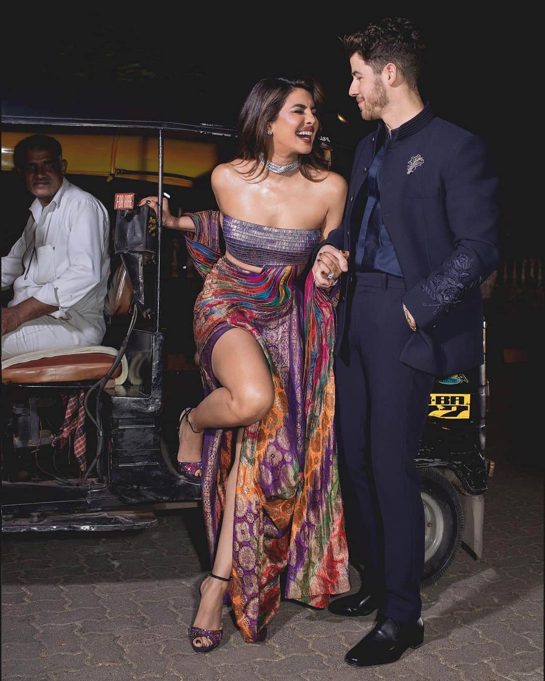 プリヤンカー・チョープラーのインスタグラム：「Date night and a 🛺…..  with my forever guy @nickjonas   Thank you @stylebyami as always for your amazing collaboration. I knew I wanted to wear an upcycled vintage look with a modern twist! So my outfit was an amalgamation of the east and the west! Like me!   Thank you @amitaggarwalofficial for coming through and creating this handcrafted beauty with a story that is so apt for an evening celebrating Indian art and Fashion.   This beautiful outfit was created using a 65 year old vintage Banarasi patola (Brocade)saree with silver threads and a gold electroplating on khadi silk. It is paired with a sequins sheet holographic bustier to reflect the nine colours of ikat weave that the brocade is set in.  Thank you for your genius Amit and your gifted team.  Congratulations #NitaAmbani and @_iiishmagish for creating an incredible exhibition of the history Indian fashion at the @nmacc.india! So proud of this exquisite space and the potential it has to promote Indian Art and design ❤️  Ps- Also for all wondering auto uncle took the cake! Was lovely and gracious! Thank you auto uncle!」