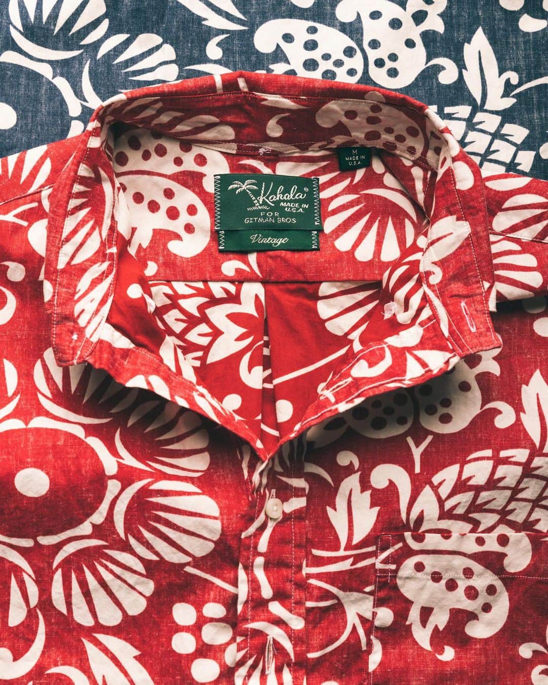 ギットマンブラザーズのインスタグラム：「Welcome back to Warp Weft Wednesday! This week we’re focusing on our collaboration with Hawaiian shirtmaker Kahala. The capsule features just a single fabric, but its significance alongside Kahala and the history of Hawaiian shirting is rather unique.  . We’ll start with this: Kahala was the first brand to make Hawaiian shirts as we know them today. The Hawaiian shirt, with its distinctly tropical motifs, dates back to 1936 when Kahala began operations in Honolulu. At that time, their shirts were sold alongside fresh fruit at a sidewalk stand in Waikiki Beach. But these humble beginnings were rather short lived. In the early 1940s, World War II catapulted Kahala’s shirts from relative obscurity to national notoriety. . With tens of thousands of American GI’s stationed in Hawaii, these mainlanders eventually caught on to the appeal of Kahala’s distinctly Hawaiian shirts and picked them up as souvenirs. After the war ended, the GI’s returned to mainland USA with their Hawaiian shirts in tow. And in nearly an instant, Hawaiian shirts were introduced to the country at large, paving the way for their popularity. . By the 1960’s Kahala began experimenting with more fabrics and styling. This is where Duke’s Pareo comes into play. Duke’s Pareo blended Kahala’s classic, tropical motifs with then-revolutionary reverse printing. By using the reverse side of the fabric as the “face” of the shirt, Duke’s Pareo appears faded and worn right out of the box. At the time of its release, it was truly groundbreaking to make something new that appeared “old.” But it was precisely this unique balance of old and new that made Duke’s Pareo Kahala’s most popular fabric. . When Kahala asked to work with us we were instantly drawn to the lived-in quality of Duke’s Pareo. As no surprise to anyone familiar with our brand, recreating archival fabrics is kind of our thing. And to continue the theme of recreation, we made Duke’s Pareo as a short sleeve popover in its original red and blue colorways, exactly as it was first released in the 1960’s.」