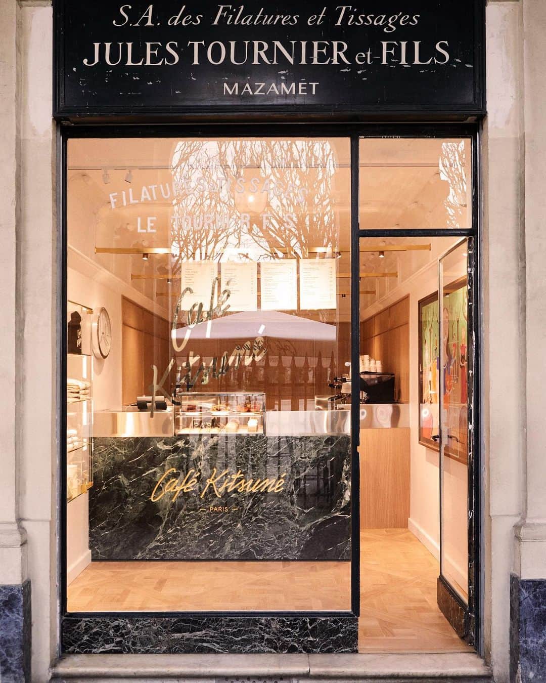 Gildas Loaëcのインスタグラム：「Authentic, Iconic, Parisian: welcome to our newly redesigned #CafeKitsunePalais Royal 🥹🥹 The Palais Royal Gardens are a symbol of Parisian authenticity and refinement. Ten years after its opening, our first historical café is still in its original space under the Gardens' signature 18th century arcades. The new decor is an elegant mix of typical French architectural elements and subtle Japanese influences. The minimalist wood panels that decorates the walls seamlessly blend with the Versailles parquet floors and intricate ceiling moldings, carefully restored. The green marble counter features a golden Café Kitsuné logo engraved on its front. Whether it's for a coffee to go or 'en terrasse, visit us to enjoy your favorite specialty drinks and pastries in a magical atmosphere, gazing over the garden's beautiful landscape. 👉🏻 Café Kitsuné Palais Royal 51 Galerie Montpensier, 75001 Paris Monday-Sunday: 9:30am-7pm #CafeKitsune #CK #ParisCafe #PalaisRoyal #ParisCoffeeShops」