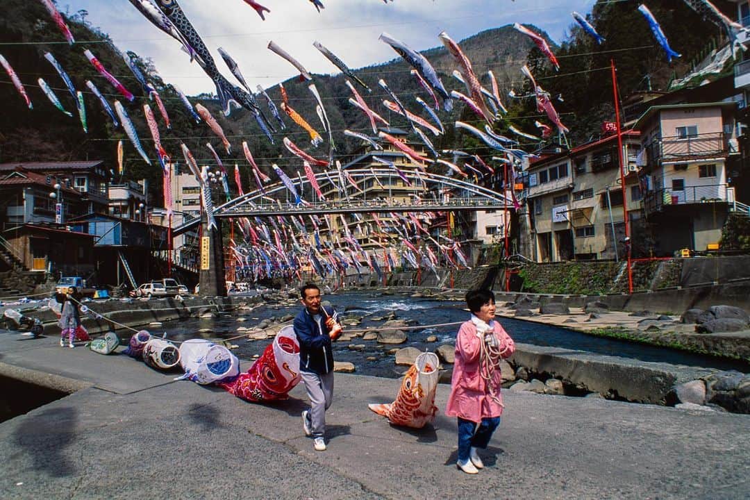 Michael Yamashitaのインスタグラム：「May 5  is Kodomo no Hi or "Children’s Day" a National Holiday in Japan and the final celebration of the Golden Week. It is a day set aside to respect children's personalities and to celebrate their happiness. Families fly koinobori banners in the shape of a carp or koi for each child in their house , which look as if they are swimming when they flutter in the breeze.In Japanese folklore, the carp is a symbol of determination and vigor, overcoming all obstacles to swim upstream. Tsuetate Onsen in Oita, Kyushu, has found a use for old koinobori, flying hundreds over the river that runs through town.  #kodomonohi #childrensday #koinobori #goldenweek #tsuetateonsen」