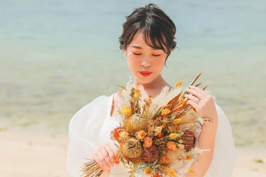 STUDIOSUNS DE&COさんのインスタグラム写真 - (STUDIOSUNS DE&COInstagram)「【ヘアメイクさんに聞きました！◎】 オレンジ🧡がよく似合う笑顔が可愛いご新婦様！！  メイクさんにこだわりポイント聞きました◎  ⬇️  こちらのお客様は、 選んでくださったのがナチュラルなドレスでした👗 ヘアスタイルはかっちりし過ぎず、沖縄の自然に合うようなナチュラルウェーブなシニヨンに♪  選んでくださった、ドライフラワーのブーケとの雰囲気とも合う様な、オレンジベースのメイクに仕上げました🧡  とのことです！  海での撮影とフクギ並木での撮影で髪飾りをチェンジしているのにもご注目👀 スワイプしてみていただくと、変化に気付いて頂けるかと！！  ブーケと同系色でまとめたドライフラワーの髪飾りは、私の推しポイントです✨  一緒になってヘアメイクや髪飾りを考えてくださる初澤さんも一緒に♡ 是非チェックしてください☑️  ------------------------------  photo / @yagasaki.deco.ph   hair&make / Miyu Hatsuzawa  studio / @studio8_nagoya  #スタジオエイト #スタジオ8 普段は愛知で撮影してます！ 愛知で前撮り、後撮り撮影もお任せください。  ------------------------------  『#撮る結婚式 という幸せを』  私たちと一緒に働きませんか？ photographer、hair&make、plannerを募集中です◎ 詳しくは...@decollte_recruit  #名古屋プレ花嫁 #結婚準備  #沖縄花嫁 #愛知花嫁 #名古屋花嫁 #フォトウェディング #前撮り #後撮り #沖縄前撮り #名古屋前撮り  #結婚写真 #ウェディングフォト #ウェディングカメラマン #カップルフォト #カップルさんと繋がりたい #前撮りポーズ #前撮りアイテム  #前撮り指示書  #ウェディングドレス #ドレス前撮り #海ポートレート #沖縄の海 #フクギ並木 #フクギ並木フォトウエディング」4月14日 12時08分 - studiosuns_okinawa