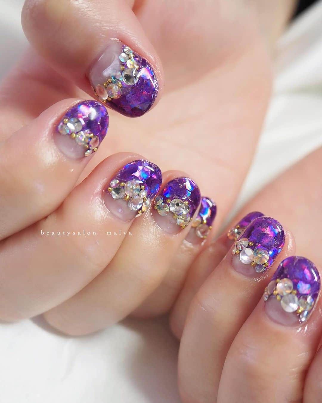 nailsalon malva（ネイルサロンマルヴァ）さんのインスタグラム写真 - (nailsalon malva（ネイルサロンマルヴァ）Instagram)「【キラキラアート002】でご予約可能✨ ⁡ パープルのホログラムが眩しいほどに ぎっしり敷き詰めた逆フレンチネイルです💅 ⁡ さかいめにのせたストーンは 爪の大きさに合わせて変えて ⁡ ロングな方も、ショートな方も似合う大きさを セレクトしてのせていきますのでお任せください☺️ ⁡ 𓂃𓂃𓂃𓂃𓂃𓂃𓂃 ⁡  𝗯𝗲𝗮𝘂𝘁𝘆𝘀𝗮𝗹𝗼𝗻  𝗺𝗮𝗹𝘃𝗮 明治神宮前駅｜原宿駅　徒歩3分 ⁡ ⁡ ⠀ ご予約・お問い合わせ ↪︎公式LINE @ malva ⁡ 　／ 　お気軽にご連絡ください♪ 　＼ ⁡ 𓂃𓂃𓂃𓂃𓂃𓂃𓂃 ⁡ ▸ ジェルネイル｜スカルプ｜ケア ▸ まつげカール｜まつげエクステ ▸ ハーブよもぎ蒸し ▸ セレクト化粧品 ⁡ ⁡ \ サロンスペース面貸し / ⁡ 原宿の竹下通りから一本はいったところ とても良い立地です✨ ⁡ 都内で場所を探している技術者さん お気軽にDMください✉︎ ⁡ 《レンタル有》 ネイルデスクチェア｜アイリストベッドワゴン｜ エステワゴン｜ リクライニング・フルフラットベッド よもぎ蒸し椅子...etc ⁡ 𓂃𓂃𓂃𓂃𓂃𓂃𓂃 ⁡ \ アシスタント・アイリストも募集中！ / ⁡ ▸リモート可オンラインの画像動画制作アシスタント ▸原宿のサロンワーク全般アシスタント ⁡ お気軽にDMください✉︎ ⁡ ⁡  #ホログラムネイル #逆フレンチネイル #ゴテゴテネイル #malva #malvaネイル #ネイル #パープルネイル #キラキラネイル  #pastelnails #原宿ネイルサロン #ネイルサロン  #表参道ネイルサロン　#明治神宮前ネイルサロン  ⁡ ⁡」4月14日 16時26分 - malva_nail