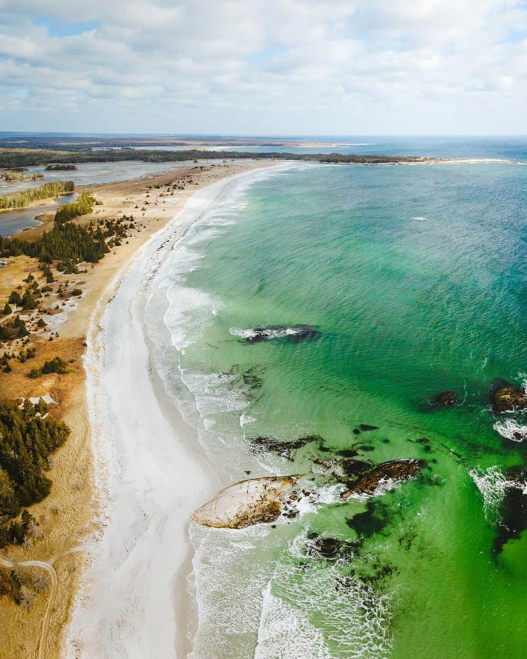 のインスタグラム：「Visit Nova Scotia for your next dose of Vitamin Sea 😎🌊  📷: @lifewithashmac 📍: @visitnovascotiasouthshore, @visitnovascotia   #VisitNovaScotia  [Image description: An aerial view of a long stretch of sandy beach next to a bright green ocean.]」