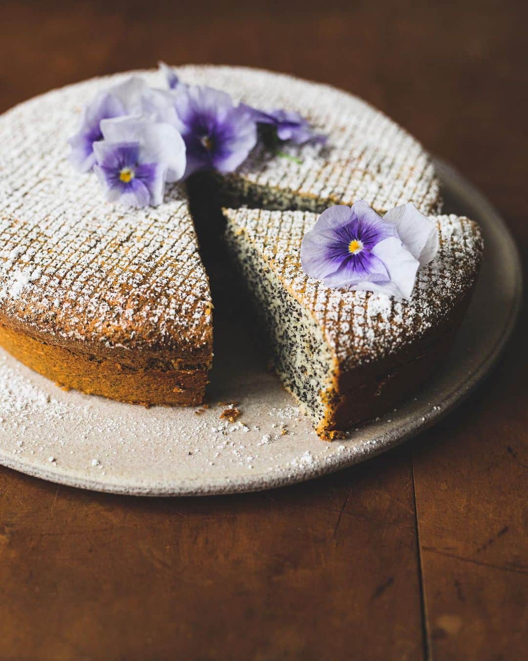 増田由希子のインスタグラム：「Homemade poppy seed cake☕️ #poppyseedcake #Mohntorte #homemade #cake #bakinglove #baking  #edibleflower #viola ウィーンのお菓子「モーントルテ」 (青いケシの実のケーキ)  美肌、リラックス効果のあるケシの実をたっぷり入れました。ナッツのような香ばしい味とプチプチとした食感がクセになるお菓子です。 エディブルフラワーは、スーパーや青果店で手軽に買えるようになりましたね。 #ビオラ　#エディブルフラワー」