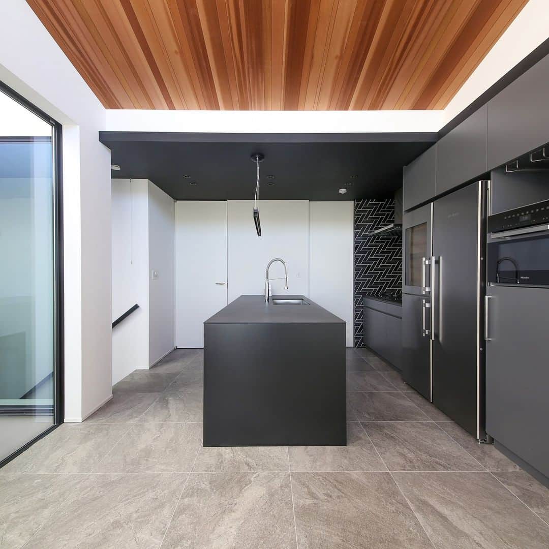 テラジマアーキテクツのインスタグラム：「インテリアに木を使うなら、床？天井？  この邸宅では黒色を基調としたミニマルで洗練されたキッチンに、板張りの天井を合わせました。 モダンで隙の無いモノトーンの空間が、リッチな印象に仕上がっています。  ・ ・  創業65年　東京・神奈川の設計事務所+工務店 @terajimaarchitects https://www.kenchikuka.co.jp/works/  #terajimaarchitects #テラジマアーキテクツ #設計事務所 #工務店 #注文住宅 #新築 #house #home #デザイン住宅 #建築実例 #luxuaryhome #beautifulhome #一戸建て #家づくり #建築家 #マイホーム #木造 #木の家 　 #モダンインテリア　 #おしゃれな家　 #心地よい家　 #家づくり計画中の人と繋がりたい 　 #マイホーム計画中の人と繋がりたい  #天井板張り #板張り天井 #モノトーンキッチン」