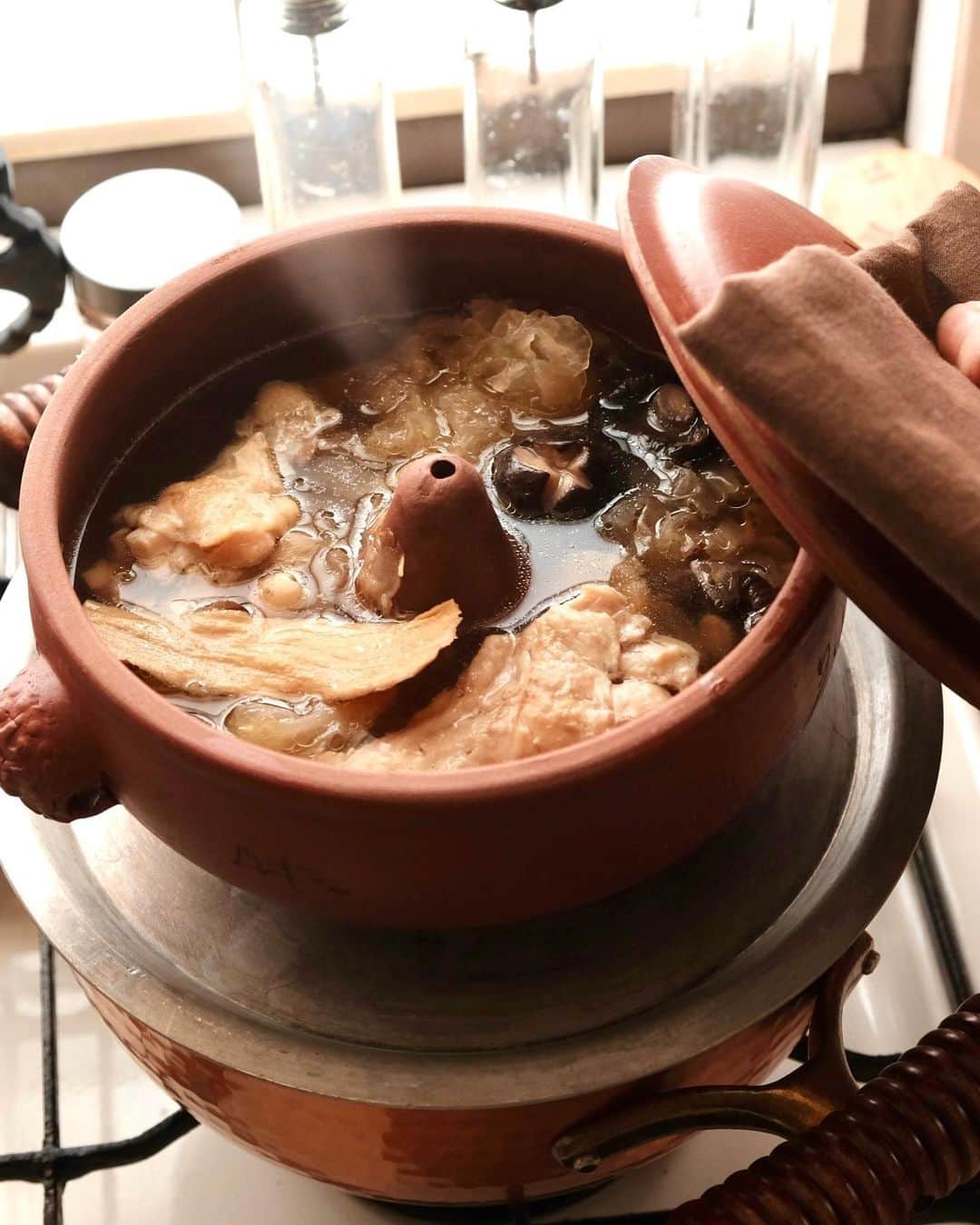 麻木久仁子のインスタグラム：「汽鍋で作る薬膳スープ💜  雲南省でよく使われている汽鍋。 鍋の中央にある突起の小さな穴から噴き上がる蒸気が、時間をかけて鍋の中でスープに変身します。  一切水を入れず、沸騰した鍋に乗せると、下から蒸気が上がってきます。 直接火にかけない、一種の蒸し鍋ですね。  スープはどこまでも澄んで、黄金色。 高級料理店に出てきそうなスープが、 簡単に作れます！ ただし。 4時間かかります🤣  でも具材を入れてあとはお任せなので、 のんびり家事でもしていれば出来上がりますよ！  『麻木のごきげん💜ひとりごはん』 動画はプロフィールのURLから。 チャンネル登録お願いします。  汽鍋はネットで買えますよ！」