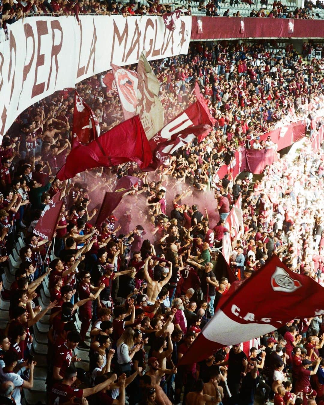 トリノFCのインスタグラム：「🇮🇹/🇬🇧 Domenica eravamo in uno stadio Olimpico Grande Torino gremito dove più di 21mila persone sono accorse per assistere alla 30esima giornata di Serie A che ha visto contro Torino e Salernitana. Due squadre che condividono lo stesso colore, il granata, e anche la stessa passione, vista l’affluenza, i cori e la voglia di spingere fino all’ultimo secondo le rispettive squadre.  Le nostre lenti si sono soffermate prima a bordo campo per osservare da più vicino i protagonisti della sfida e poi nella Curva Maratona, un nome scelto per la presenza, nello stadio comunale di Torino, nell’area retrostante la curva stessa, della “Torre Maratona”, alta 42 metri e simboleggiante lo spirito di sacrificio degli atleti.  Una curva storica in Italia, famosa per il suo attaccamento alla squadra e ai suoi colori, tant’è che fu deciso di ritirare la maglia nº 12, assegnandola simbolicamente alla Maratona. Qual è il vostro scatto preferito? -  On Sunday we were in a packed Stadio Olimpico Grande Torino where more than 21.000 people flocked to watch the 30th Serie A match between Torino and Salernitana. Two teams that share the same colour, granata, and also the same passion, given the turnout, the chants and the desire to push their respective teams until the last second.  Our lenses lingered first on the sidelines to get a closer look at the protagonists of the challenge and then in the Curva Maratona, a name chosen for the presence, in the area behind the curve itself, of the 'Torre Maratona', 42 metres high and symbolising the athletes' spirit of sacrifice.  It is a historic curve in Italy, famous for its attachment to the team and its colours, so much so that it was decided to retire the No. 12 jersey, symbolically assigning it to the Maratona. What is your favourite shot?  📸 @sonyakarate / @emanveledangelo」