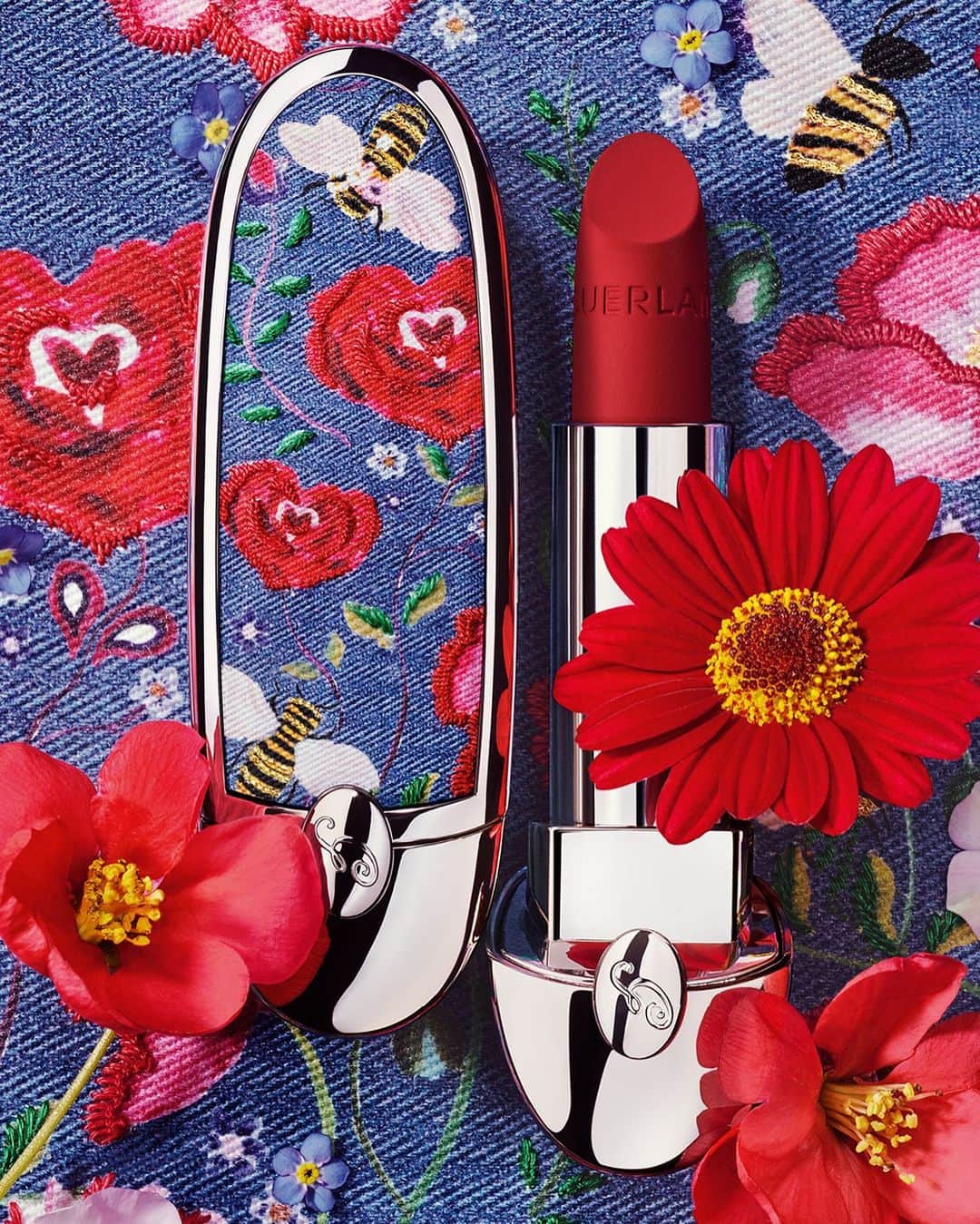 ゲランのインスタグラム：「Rouge G: the Love Jean case. The new style icon for summer.​ Brightly coloured heart-shaped roses bloom under the summer sun on exquisite blue denim - the perfect counterpart to Rouge G Luxurious Velvet 880 Ruby Red.​  #Guerlain #GuerlainMakeup​ #RougeG」