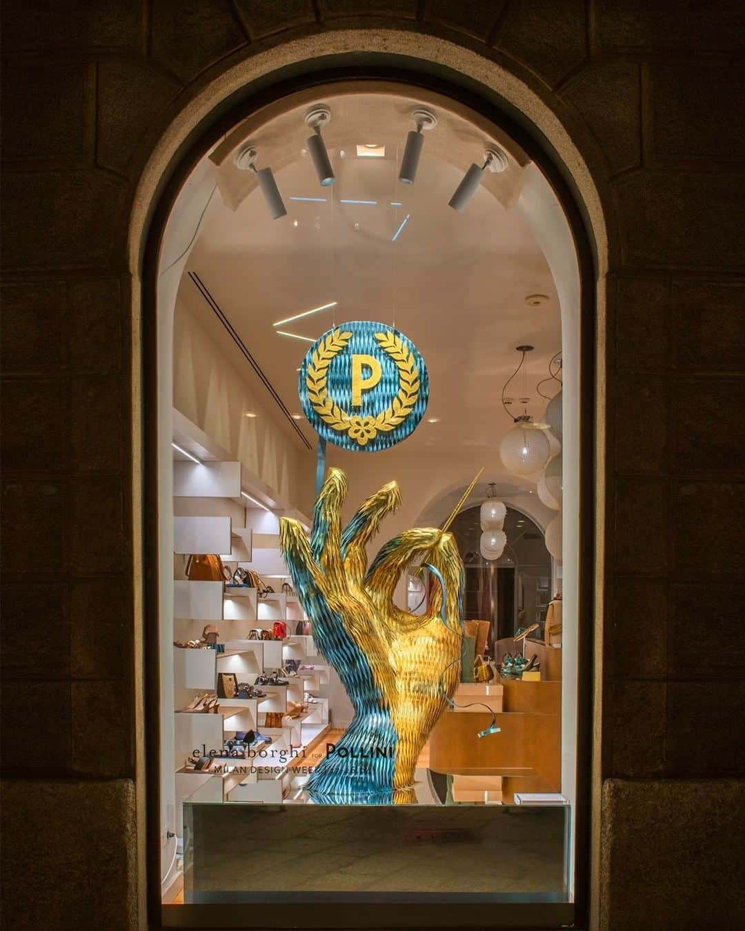 ポリーニのインスタグラム：「Hands that sew, hands that create, hands that hold 70 years of artisanal savoir-faire. Pollini celebrates its history of excellence and tradition with the sculpture “Mani d’oro”, by designer @elenaborghi, on view in the Via della Spiga boutique during #MilanoDesignWeek. The dramatic installation, completely clad in leather, depicts a gigantic hand stitching the iconic Laurel P logo.  #Pollini #Pollini70YearsOfWonders #MDW #Fuorisalone2023」