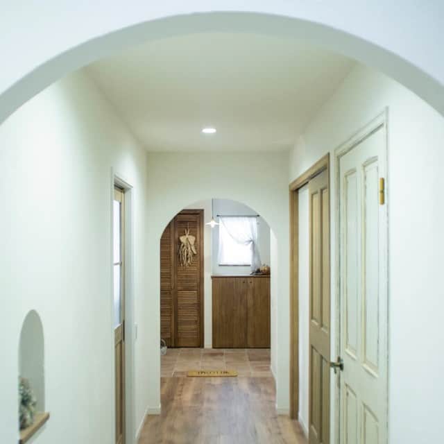 パパママハウスのインスタグラム：「. 玄関から続く廊下の天井は アーチを施し優しくお出迎え。 さりげなくこだわりを入れることで 作り上げられたおしゃれな景色です。  ナチュラルな木の扉が 真っ白な廊下のアクセントに。  壁にはニッチを作り 好みのインテリアを飾るのも素敵ですよ。  ------------------------------  ホワイト×木目でまとめた 居心地の良いダイニング。  明るく優しい光がたくさん入り 楽しく食事がしやすい空間です。  家族の会話に華が咲いている そんな様子が目に浮かびます。  ------------------------------  洗面台スペースはフラットにして気持ちよく。 優しさのあるインテリアと シンプルなのに可愛さのある 洗面台がマッチしています。  シェルフや鏡、洗面台にも木を採用し、 とことんあったかい印象に ライトの丸いシルエットが可愛らしいですね。  ------------------------------  こだわりのアーチはリビングにも採用！  好みのアンティーク家具にテイストを合わせ シャービックな空間づくりを意識しています。  梁やドアは上手に木目を取り入れて。  ホワイトなのにあったかい印象のある そんな素敵スペースです。  ------------------------------  ライトにもアンティークらしさをプラス。 これがあるのとないのでは お部屋の印象が全然違く見えますよね。  こだわりの一点ものだからこそ 個性が発揮できるように 配置するのがおすすめです。  ------------------------------  愛知、岐阜、三重で お家づくりを考えている方大歓迎！  今だけ150ページの大容量で 90件のお家事例を紹介している 「家と暮らしカタログ」 をプレゼント中♪  詳細はプロフィールから @papamamanhouse ㅤㅤㅤㅤㅤㅤ  #注文住宅 #丁寧な暮らし #マイホーム計画 #新築一戸建て #ナチュラルインテリア #自由設計 #施工事例 #デザイン住宅 #おしゃれな家 #モデルハウス #一宮市 #店舗デザイン #かっこいい家 #好きなものに囲まれた暮らし #完成見学会 #家づくりアイデア #注文住宅新築 #高断熱 #設計士とつくる家 #高気密 #失敗しない家づくり #理想の家 #デザイナーズハウス #ペットと暮らす家 #スタイリッシュな家 #内観デザイン  #パパママハウス #家づくり日記 #大好きな暮らしを #愛知住宅」