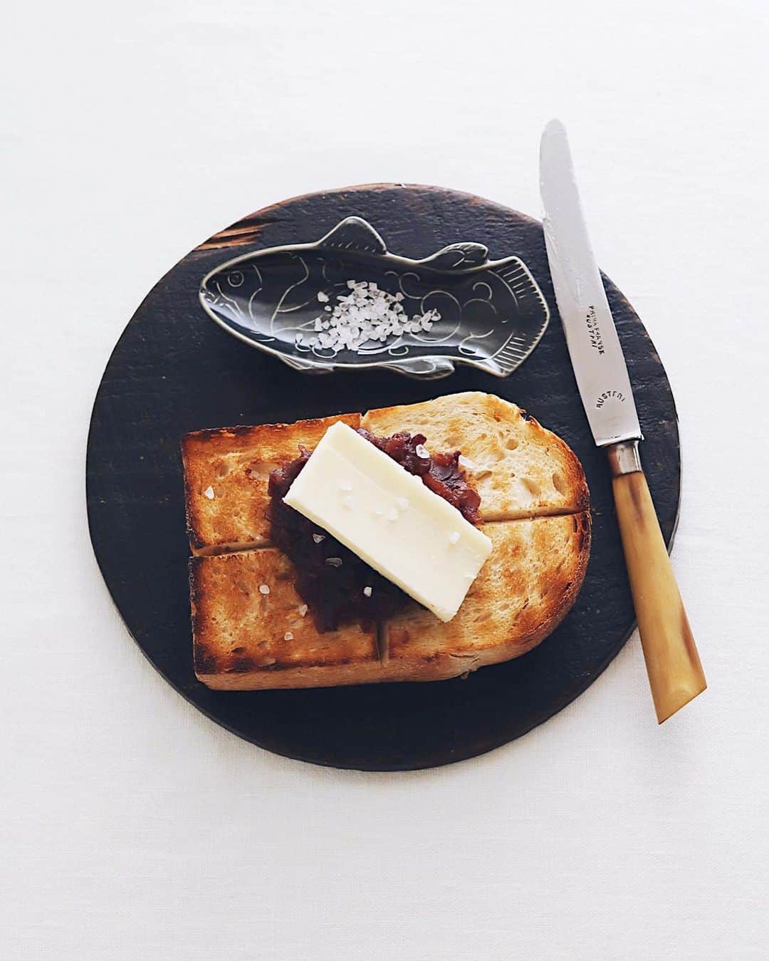 樋口正樹のインスタグラム：「Anko butter toast . 朝ごはんのあんバタトースト。 厚切りの食パンを網焼きして、 粒あんと無塩発酵バターのせ、 仕上げに上から粗塩をぱらり😋 . 魚の形のお皿を探していたら 有田焼のまるぶんのサイトで シーラカンスの黒くマットな 小皿を見つけてしまい、捕獲🤗 @aritayaki_marubun . . . #あんバタ #あんバター #あんバタートースト #厚切りトースト #有田焼 #シーラカンス #まるぶん #まるぶんのうつわ #アリタセラ #器のある暮らし #器好き #aritayaki #marubun #toastgram #ankobutter」