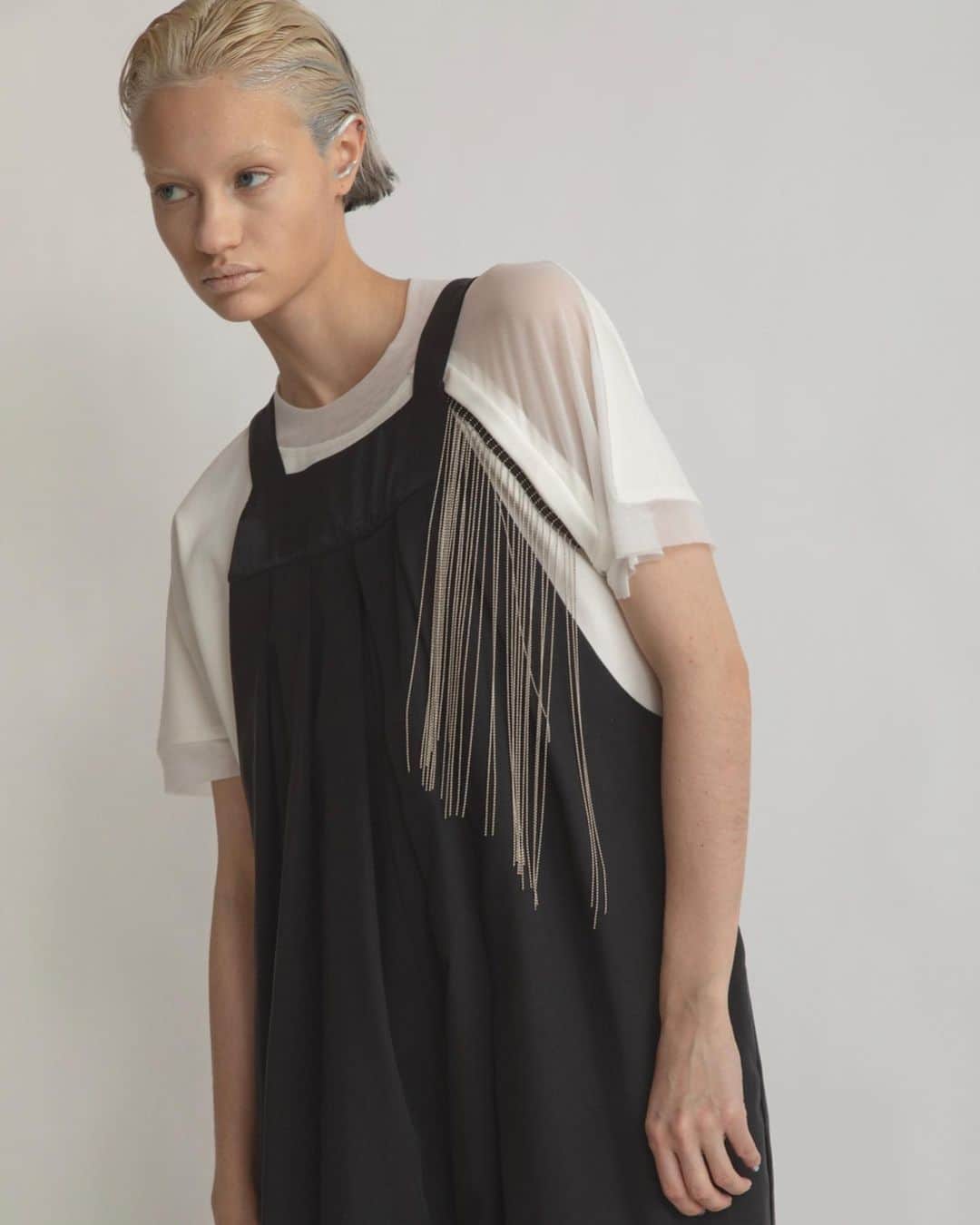 AULA AILAのインスタグラム：「【2023 HIGH SUMMER COLLECTION】  TACK SALOPETTE COLOR BLACK SIZE 0/1 ¥25,300   ワイドシルエットのリラックス感漂うサロペット。 リネンシルクのさらりとした素材感で、真夏にピッタリのアイテム。 胸元のディテールは、ホルターネックのような浅めでコンパクトな衿元にすることでカジュアル過ぎず、フェミニンで華奢な印象に。 裾は部分的にソフトオーガンジーをはめ込み透け感をプラス。  CHAIN FRINGE T-SHIRT COLOR OFF WHITE SIZE 0 ¥16,500  ボールチェーンのフリンジ付きのTシャツ。 左胸から垂れるフリンジは、動くと揺れてアクセサリーが付いているようなデザイン。  フリンジはドットボタンで簡単に取り外したり付けたりできるので、スタイリングやシーンに合わせてであったり、お洗濯の際に外してお手入れして頂けます。 襟ぐりと左肩から袖は、シアーチュールで切り替えて、肌が透けるので、フリンジを外しても素敵なデザインTシャツ。  ✔️AULA AILA OFFICIAL WEB STOREにて HIGH SUMMER COLLECTIONアイテム展開中！」