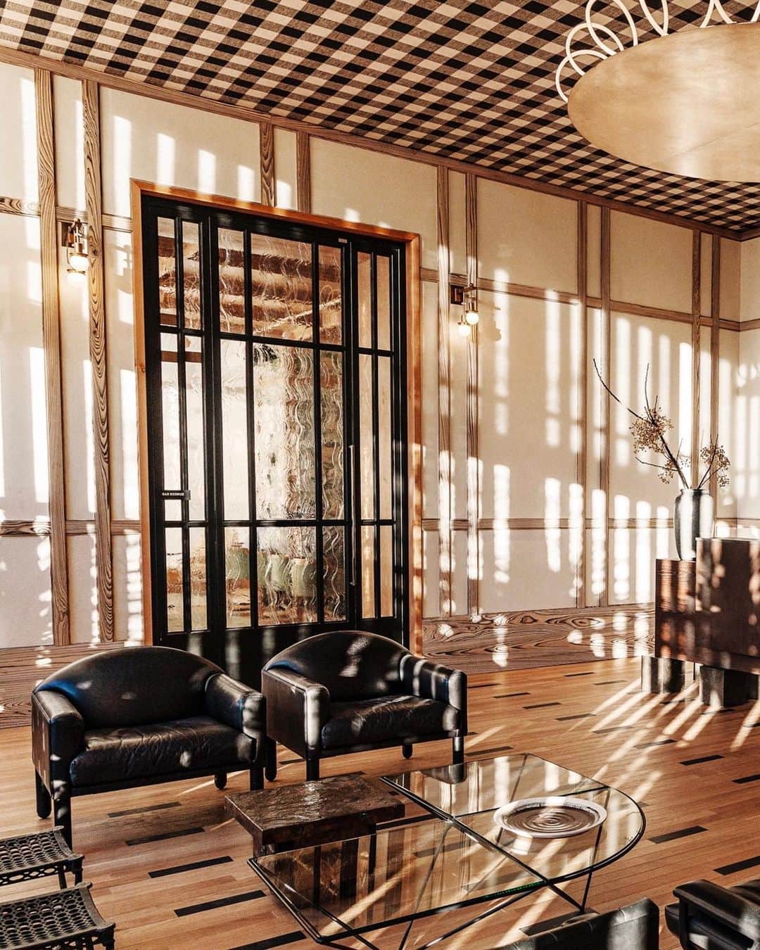 ケリーウェアスラーのインスタグラム：「IN A NEW LIGHT. At the @austinproperhotel a seven-foot-wide brass ceiling fixture by Italian designer Massimiliano Locatelli doubles as a sculptural statement. Throughout the hotel, Austin-based suppliers and craftsmen were used wherever possible. In the lobby, the cypress wood millwork was sourced locally. The large cast-ceramic wall artwork, made by an unknown artist, was sourced at a local flea market in Texas. Starkly modern elements contrast with folksy local finds, including a pair of Pierre Chareau re-edition sconces placed next to a vintage framed needlepoint work by an unknown artist. XK」