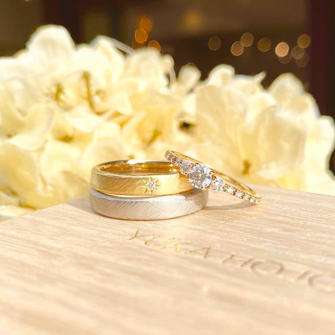 JKプラネット銀座.表参道.福岡|結婚指輪セレクトショップのインスタグラム：「💍YUKAHOJO- ユカホウジョウ 婚約指輪 Comet-コメット- 結婚指輪 Weave -ウィーブ-  ご紹介したリングの他の投稿はこちら🌿 #YUKAHOJOコメットJKPLANET  #YUKAHOJOウィーブJKPLANET ………………………………………………………………  婚約指輪は、繊細なリングに 大きめなダイヤモンドが両サイドにあしらわれ とても華やかでスタイリッシュなデザイン✨  結婚指輪は、ふたりで織り上げる ふたりの人生を一枚の布にイメージ🧶 あたたかく包み込んでくれるような指輪です♡  ┈┈┈┈┈┈┈┈┈┈┈┈┈┈┈┈┈┈┈┈ 　 婚約指輪 ¥331,100〜 [K18YG]  結婚指輪 Men's ￥178,000［Pt950］ Lady's ￥168,300 ［K18YG］ 　  ┈┈┈┈┈┈┈┈┈┈┈┈┈┈┈┈┈┈┈┈ 　 YUKA HOJO取り扱い店 銀座本店・銀座2丁目店・表参道店・横浜元町店・大宮店・名古屋栄店・福岡天神店・熊本上通店・宮崎橘通り店・鹿児島天文館店  　 @jkplanet.jewelry SHOP LIST  銀座本店・銀座2丁目店・表参道店・横浜元町店・大宮店・名古屋栄店・福岡天神店・熊本上通店・宮崎橘通り店・鹿児島天文館店  ┈┈┈┈┈┈┈┈┈┈┈┈┈┈┈┈┈┈┈┈  #JKPLANET#JKプラネット #YUKAHOJO#ユカホウジョウ #マリッジリング#結婚指輪 #エンゲージリング#婚約指輪 #marry花嫁#花嫁#プラコレ #ウェディングニュース #ゼクシィ#dressy花嫁 #指輪#みんなのウェディング  #weddingring#weddingrings #ウェディング#ウエディングドレス #プロポーズ#入籍#結婚 #プレ花嫁結婚式#プレ花嫁  #ブライダル #gold #diamond」