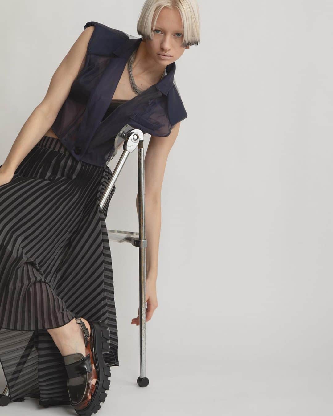 AULA AILAのインスタグラム：「【2023 HIGH SUMMER COLLECTION】  SHEER TAILOR SHORT VEST COLOR NAVY SIZE 0 ¥18,700  表がチュール、裏がソフトオーガンジーの2枚仕立ての、シアーテーラーベスト。 左のテーラーカラーは、ダーツから繋がる変形襟で、アシンメトリー。 胸ポケットの袋布が裾から除くデザインや、ダーツを表に出し配色ステッチを入れるなど、細かいディテールにこだわった他にはないデザイン。 肩パットや、縫い目、ポケット袋布の透けや、襟や胸ポケットなど、重なる部分のシアー感が洗練された大人な印象。   STRIPE PRINT PLEATS SKIRT COLOR BLACK×GRAY SIZE 0 ¥23,100  細いプリーツとストライププリントの加工を施したオリジナル生地をレイヤードしたスカート。 内側スカートは左裾にスリットが開いたタイトラインで、表スカートは広げると長方形になるデザイン。 プリーツとストライプの縦柄効果が、造形的でシャープな印象のスカート。 歩くと様々な形に広がったり、静止するとウエストからすとんと落ちたり、様々に表情を変える他にはないデザイン。  ✔️AULA AILA OFFICIAL WEB STOREにて HIGH SUMMER COLLECTIONアイテム展開中！」