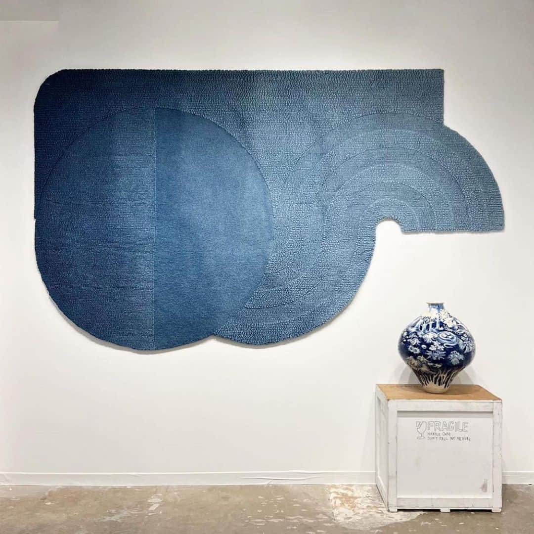 KEISUKE SYODAのインスタグラム：「Wavy rug in indigo : @peteraugustusgallery for The Dallas art fair💙 Thank you for having my piece out there. Beautiful masterpiece I made with @ryukyu_indigo_labo . 糸から藍を使って染めることは出来ても製品染めと呼ばれるいわゆる、製品が出来上がってからの染めはなかなかハードでリスキーなもので、 藍といえば高級な自然の染料と呼ばれています。 特に何百キロと刈り取った藍葉から染料にできるのはごくわずかで、こんなに大きなものを染めるのはとても高価で誰もあまり正直やりたがらないとそんな声も最初に上がりました。 . 藍の色は48色あると言われています。 そのShades of indigoを1枚のこのWavy rugに落とし込み約1ヶ月半かけ形にしました。 . 今回使用したのは琉球藍と呼ばれるもので、藍の栽培、耕作のための土壌作り、管理技術を一つ一つ自らの手で行った @ryukyu_indigo_labo さんの力を借りて、世界に一つだけの藍染ラグが誕生しました。 沖縄の伝統工芸である琉球藍と京都の南丹の伝統技術であるラグのタフト技術、２つの伝統工芸がこうして１つのピースになって沢山の人の目に触れらるということはとても嬉しく、私もデザイナーとしてもっと沢山の伝統工芸技術を後世へ継承していけるよう発信していけたらとつくづく思うのです。」