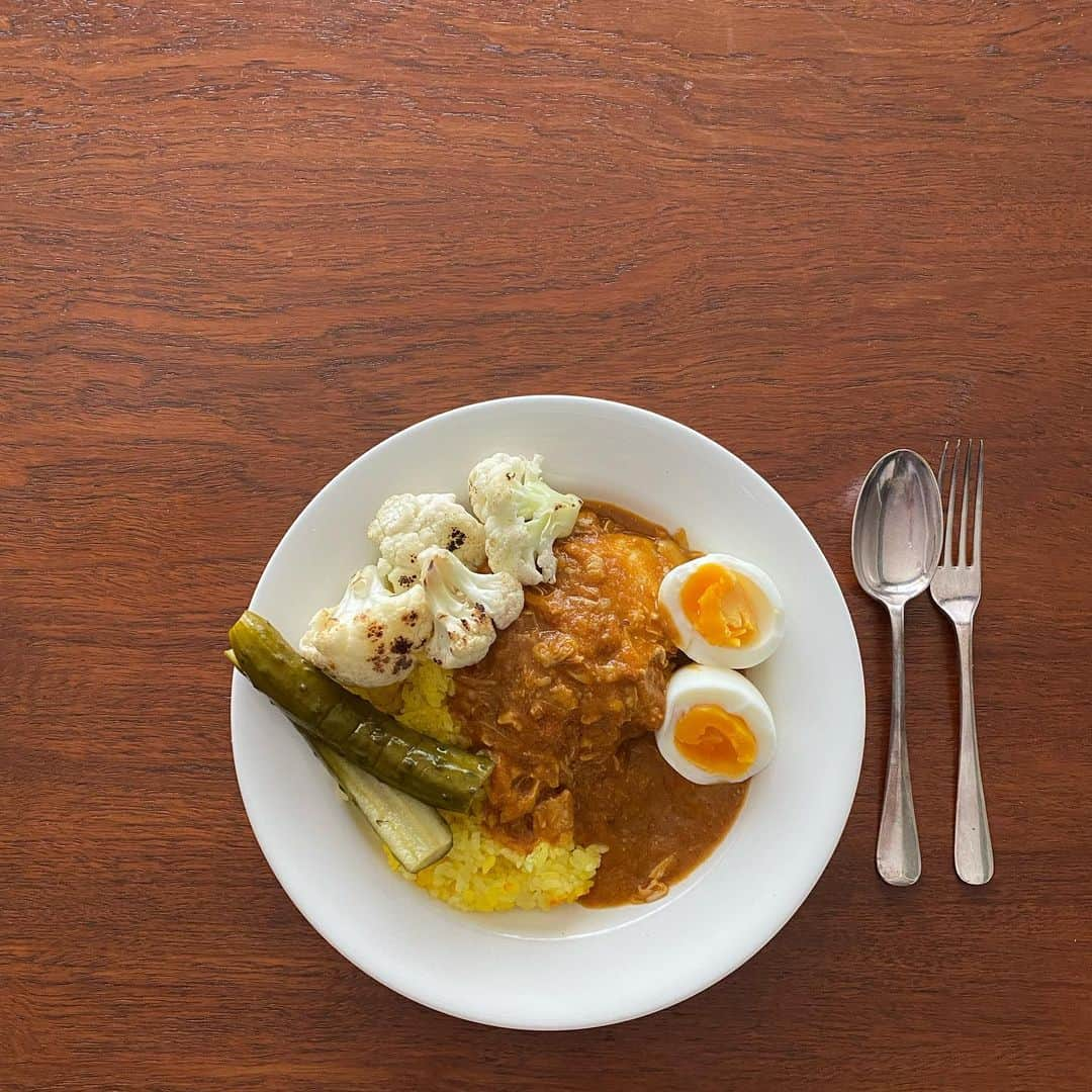 伊藤まさこのインスタグラム：「完熟トマトと新玉ねぎのチキンカレー。鶏は骨つき、水分は野菜のみ。煮込んで一晩置いたらチキンを取り出し煮汁をプロセッサーにかけて滑らかに(その後またチキンを戻す)。トマトは1週間前に買って真っ赤になる頃合いを見計らって使用。手間も時間もかかるけれどその分、味に返ってくる。忙しい時ほどこういう料理が作りたくなるのはなぜ(😮‍💨)。添えたのはサフランライスに手作りピクルス、鉄のフライパンで焦げ目をつけたカリフラワー、ゆで卵。鋼正堂のスーププレートはカレーにも合います。」