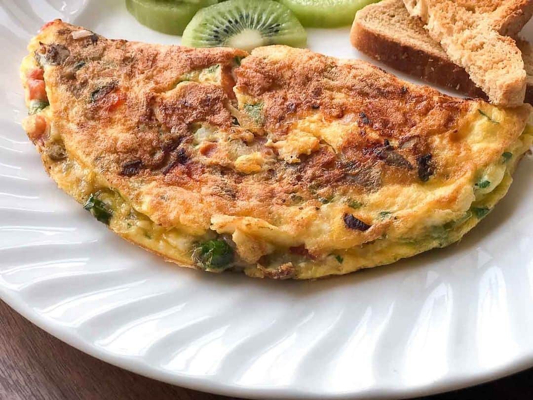 Archana's Kitchenのインスタグラム：「Make this wholesome and protein-packed Mushroom Masala Cheese Omelette that is soft and fluffy. Serve it along with toast, fruits, and a cup of hot coffee for a wholesome breakfast.  Ingredients 2 Whole Eggs 10 Button mushrooms, roughly chopped 1/2 Onion, finely chopped 1 Green Chilli, finely chopped 1/2 Tomato, finely chopped 4 Black olives, finely chopped 1 tablespoon Cheese, grated Coriander (Dhania) Leaves Salt and Pepper, to taste 1 teaspoon Oil, for cooking  👉To begin making Mushroom Masala Omelette Recipe, first prep all the ingredients and keep them ready. 👉In a mixing bowl, break the eggs and whisk them up well along with salt, pepper, olives, cheese and tomatoes. Keep this aside. 👉Heat oil in an omelette pan over medium heat; add the mushrooms, onions and green chillies and saute until the onions and mushrooms are slightly roasted.  👉Once roasted, add the egg omelette cheese mixture into the roasted onion and mushrooms. 👉Swirl the pan to spread the omelette mixture and gently combine the onions and mushrooms and spread it around. 👉Keep the heat on low and cook the omelette until you notice the top is getting steamed and cooked. You can also optionally cover the pan and cook the omelette faster. 👉Once the top is cooked, fold the omelette into half and cook for another few minutes is required and turn off the heat. You can also optionally flip the omelette and cook it on both sides. 👉Serve the Mushroom Masala Omelette along with a Toast, fruits and a cup of Masala Chai or Filter Coffee.  Find 1000+ such recipes on our app "Archana's Kitchen" or website www.archanaskitchen.com . . . . . #recipes #breakfast #breakfastideas #breakfasttime #breakfastbowl #breakfastlover #poha #tea #teatime #southindianfood #southindianrecipes #southindianfood #homemadefood #eatfit #cooking #food #healthyrecipes #foodphotography #recipeoftheday #comfortfood #deliciousfood #delicious #instayum #food」