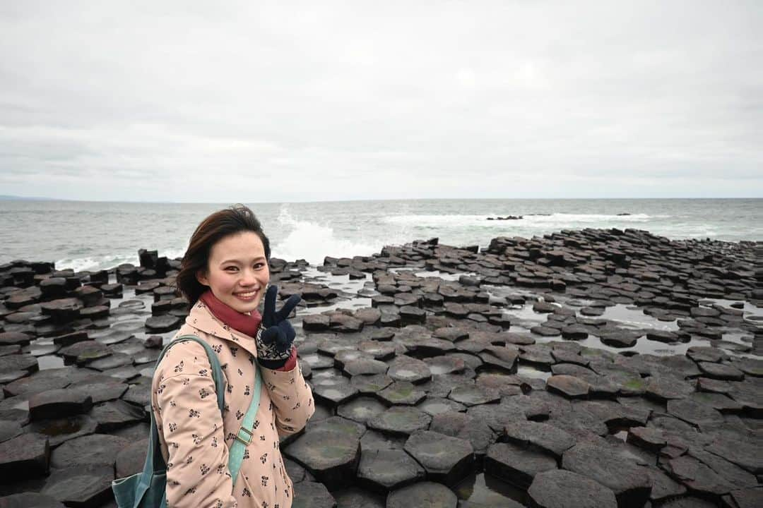 岡本沙紀のインスタグラム：「Dia dhuit! 🇮🇪🍀 ⁡ 今日の挨拶はアイルランドの言語であるゲール語です🇮🇪 ⁡ 世界遺産シリーズ第三弾はジャイアンツコーズウェイです🧌💎 ⁡ ジャイアンツコーズウェイは、アイルランド北岸の海岸線にある、六角形の柱状節理からなる自然の景観です。これらの柱は、溶岩が急速に冷え固まったときにできた規則的なひび割れに由来します。1986年に世界自然遺産に登録されました。 ⁡ フェリーでブリテン島から北アイルランドの首都ベルファストまで行き、そこからさらに2時間以上バスに乗って行ったのは大変でしたが、長年の念願叶って来訪できてよかったです。 ⁡ “Giant’s causeway” というのは直訳すると「巨人の石道」という意味で、アイルランドの伝説的な英雄フィン・マックールが巨人と戦うために作り上げた道だと言い伝えられているそうです。 ⁡ 現地は風が強く大変寒かったです😂 また巨人用の道だからなのか段差が大きい場所や急に切り立っている場所があり、かなり歩きにくかったです💃 ⁡ Dia dhuit! 🇮🇪🍀 ⁡ Today's greeting is in Gaelic, the language of Ireland: 🇮🇪 ⁡ Third in our World Heritage Site Introduction series is the Giant's Causeway🧌💎. ⁡ The Giant's Causeway is a natural landscape of hexagonal columnar joints on the north coast of Ireland. These columns are derived from cracks formed when lava cooled and solidified rapidly. ⁡ It was a long and arduous way to get there with an all-night ferry ride and two-hour bus trip, but I am glad to be at the place that has been on my wishlist for a long time. ⁡ "Giant's causeway" means "Giant's stone path" in literal translation. There is a legend that the path was built by Irish hero Finn McCool to fight giants. ⁡ It was very cold and windy, and there were some places where the steps were relatively high💃 Be careful when you walk there unless you’re a giant!🧌 ⁡ ⁡ #WorldHeritageSite #世界遺産 #世界自然遺産 #giantscauseway #ジャイアンツコーズウェイ #northernireland #北アイルランド #nationaltrust #japanesegirl #uktravel #イギリス留学 #英語学習 #東大王 #nikonz30」